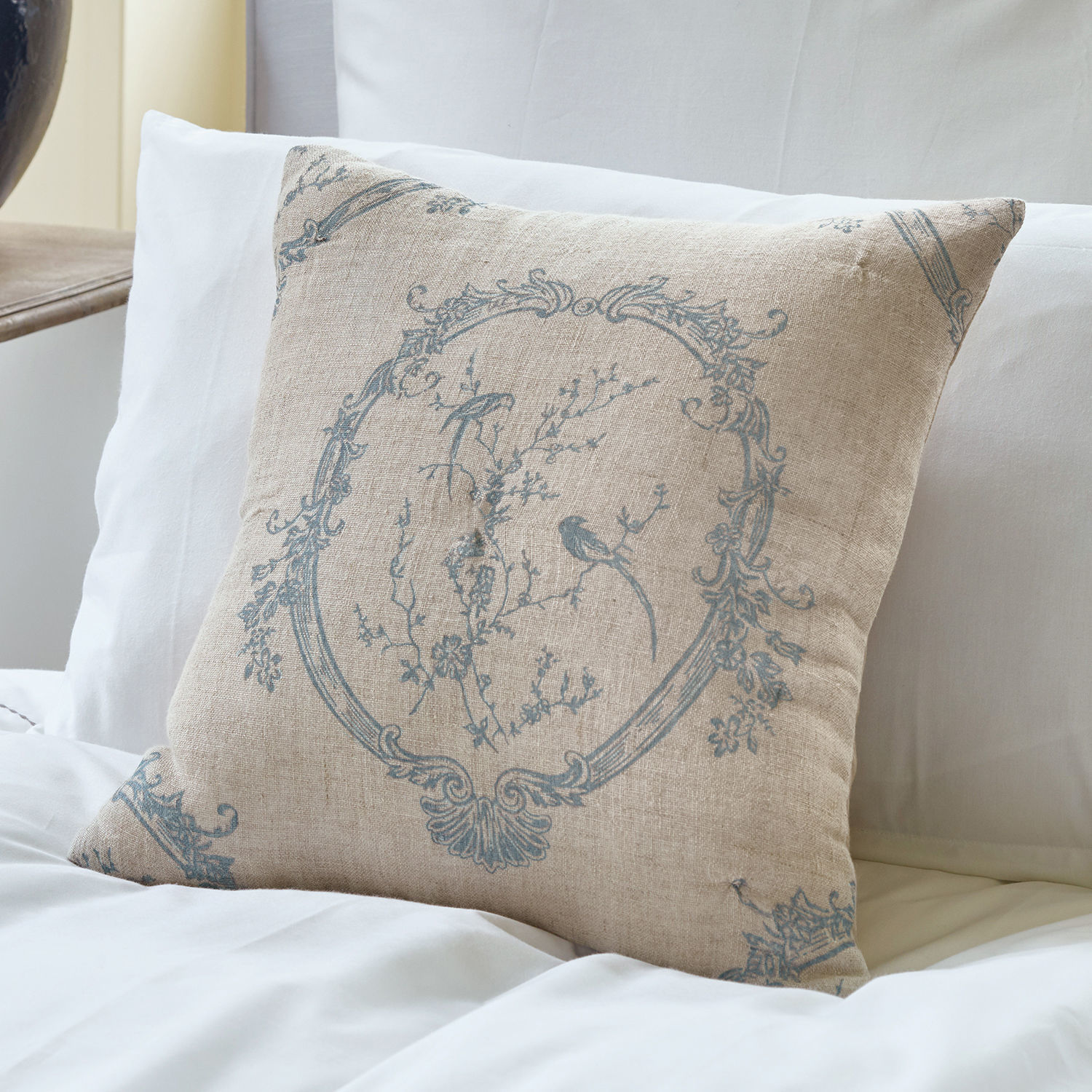 Funda de cojín Decadence Cojín beige de lino con diseño azul de pájaros y flores sobre ropa de cama blanca, decoración para dormitorio