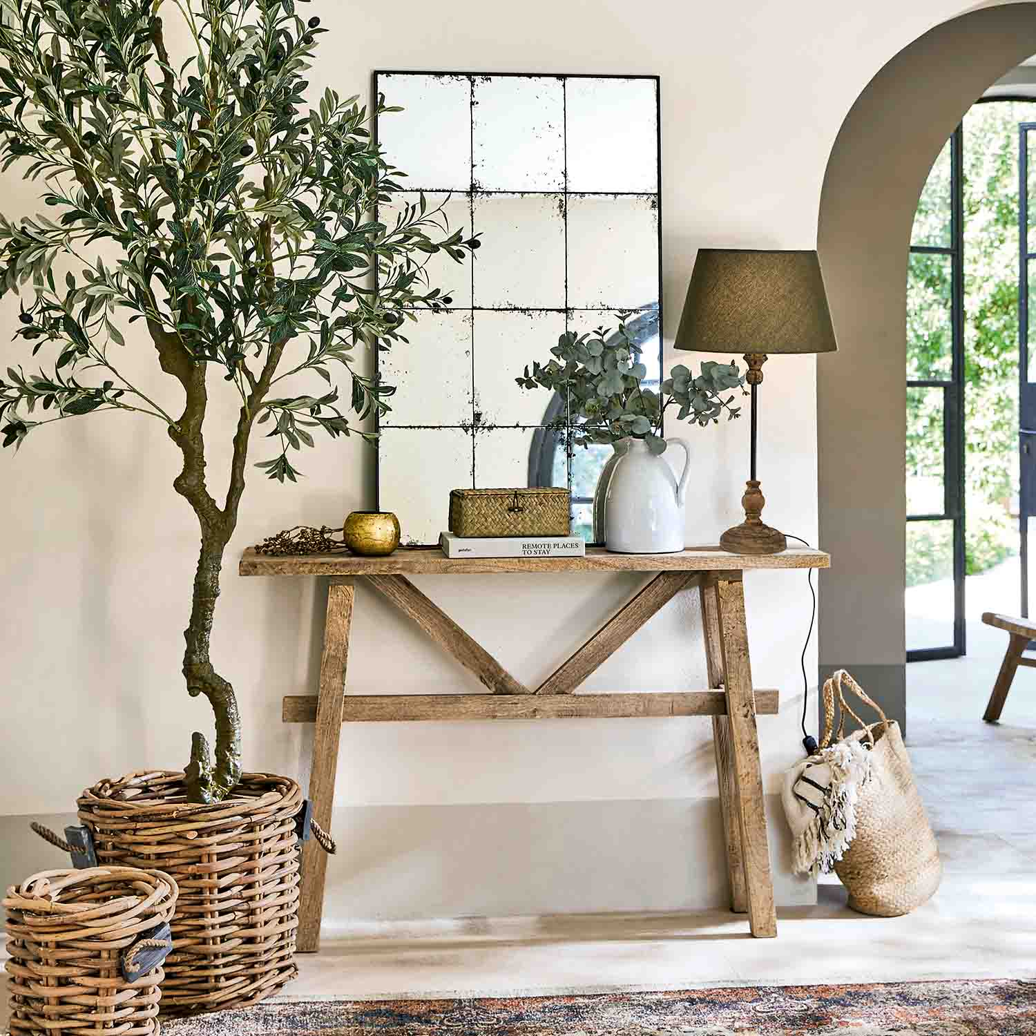 Consola de madera con espejo, lámpara y decoraciones de mimbre en interior luminoso y natural