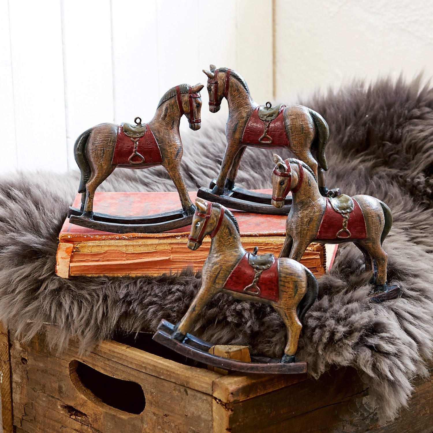Set de 4 caballos decorativos Cory Conjunto de cuatro caballos mecedores de madera marrón con sillas rojas para decoración rústica.