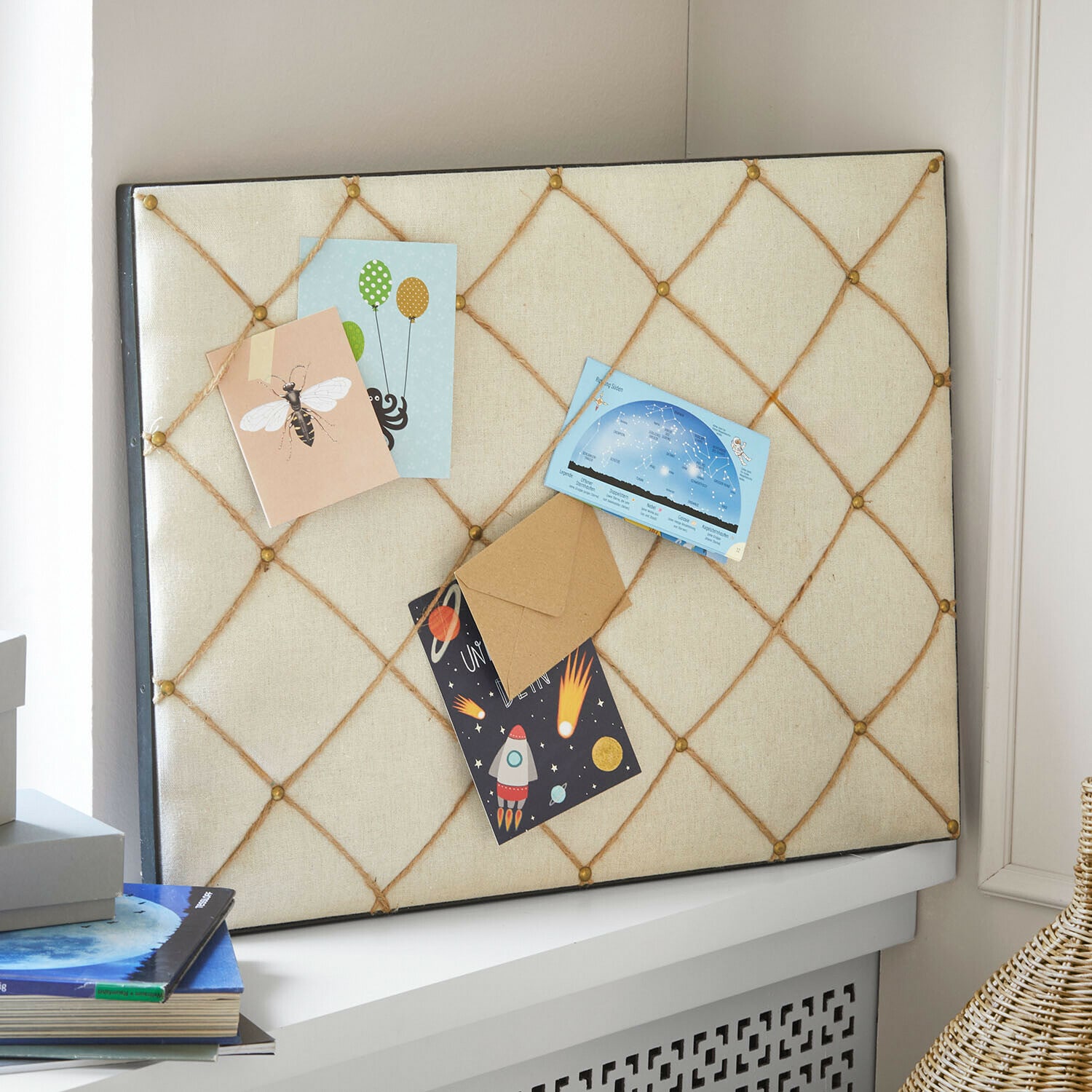 Tablero de corcho con tela beige y cuerdas para sujetar notas y tarjetas en una habitación