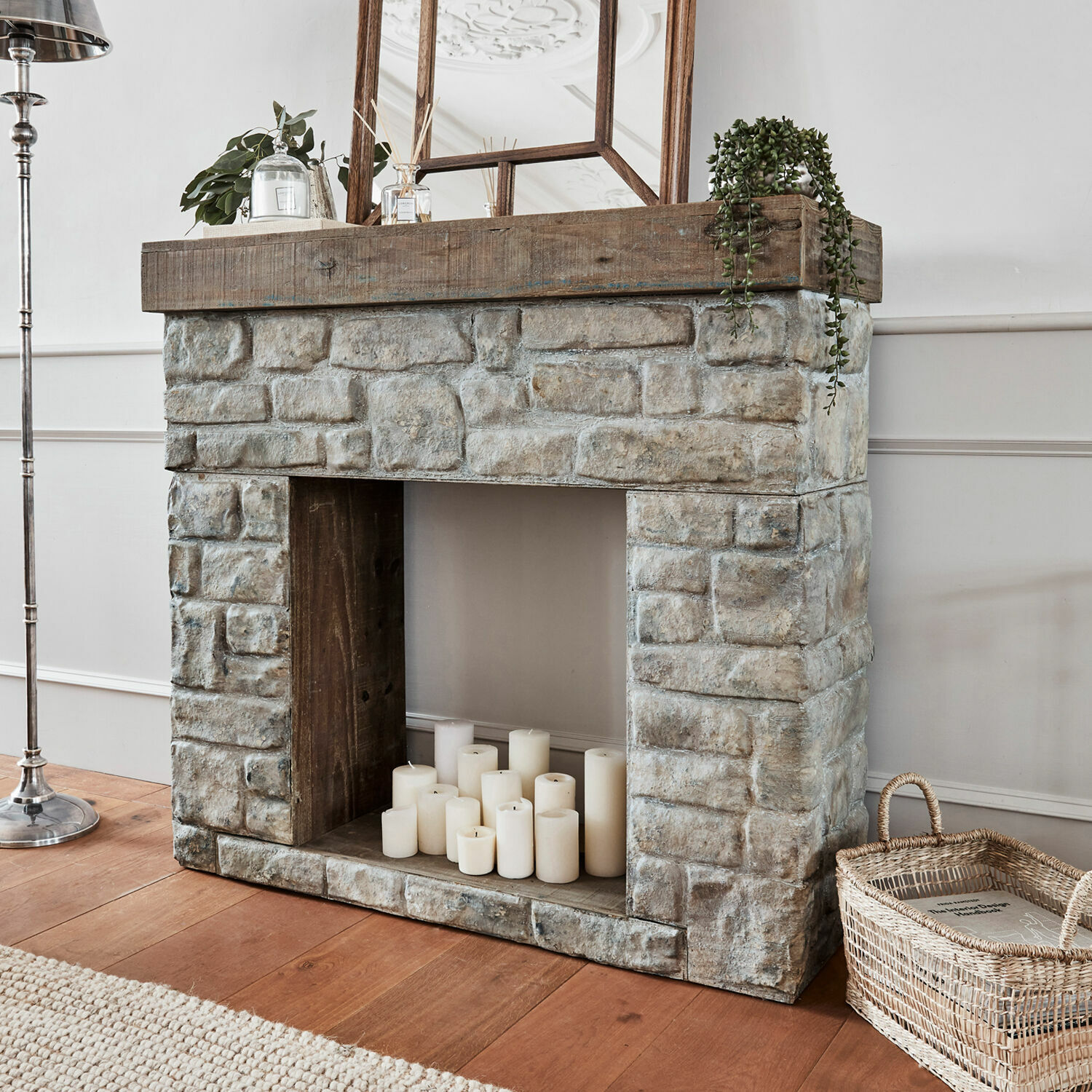 Consola de chimenea Evreux Chimenea decorativa de piedra gris y madera con velas blancas y cesta de mimbre
