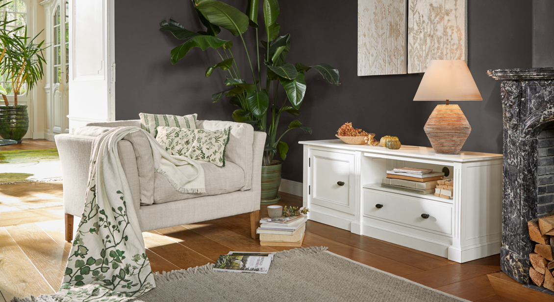 Sala acogedora con sofá beige, aparador blanco y plantas verdes, estilo escandinavo
