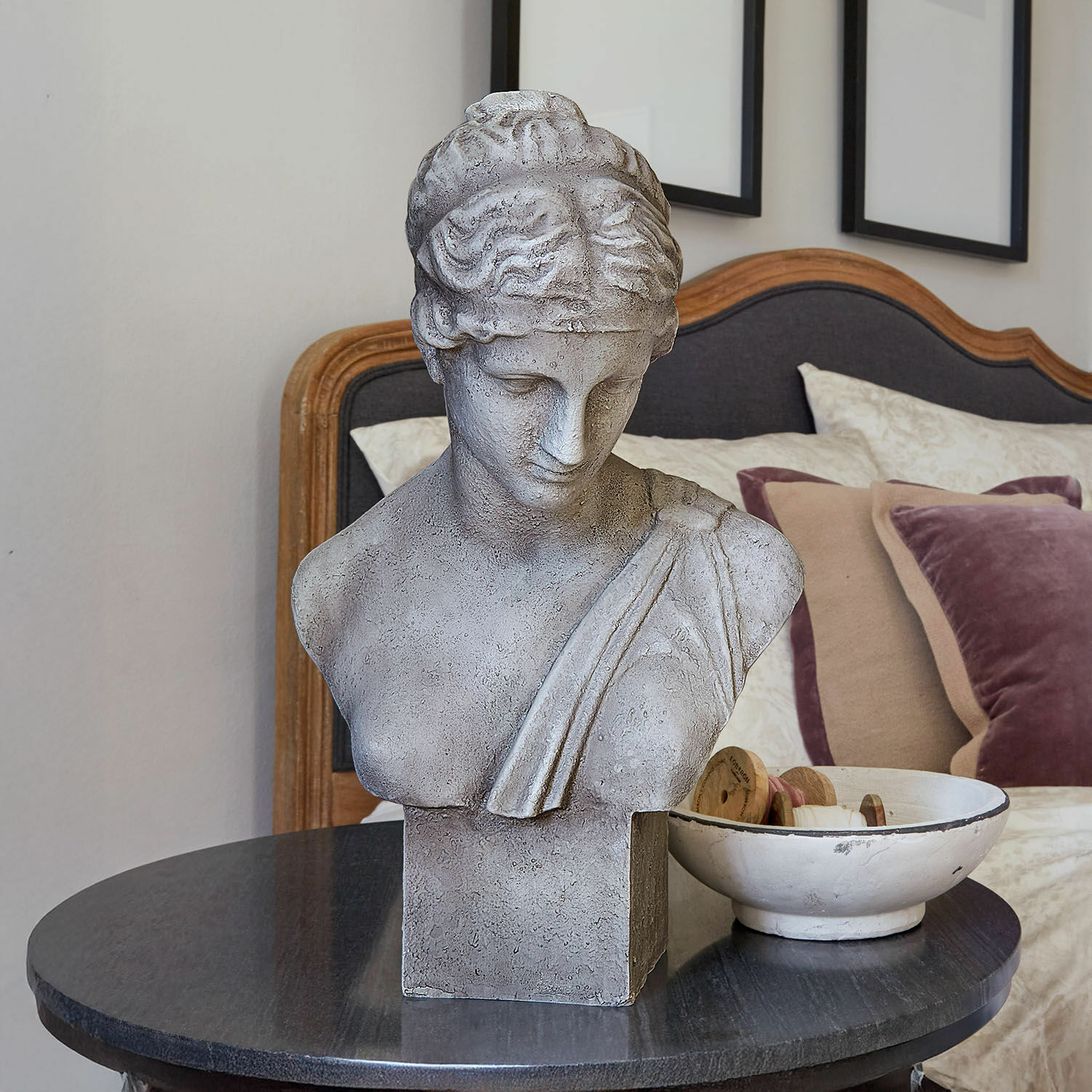 Busto Castolio Busto de piedra gris sobre mesa negra en interior elegante con cojines decorativos