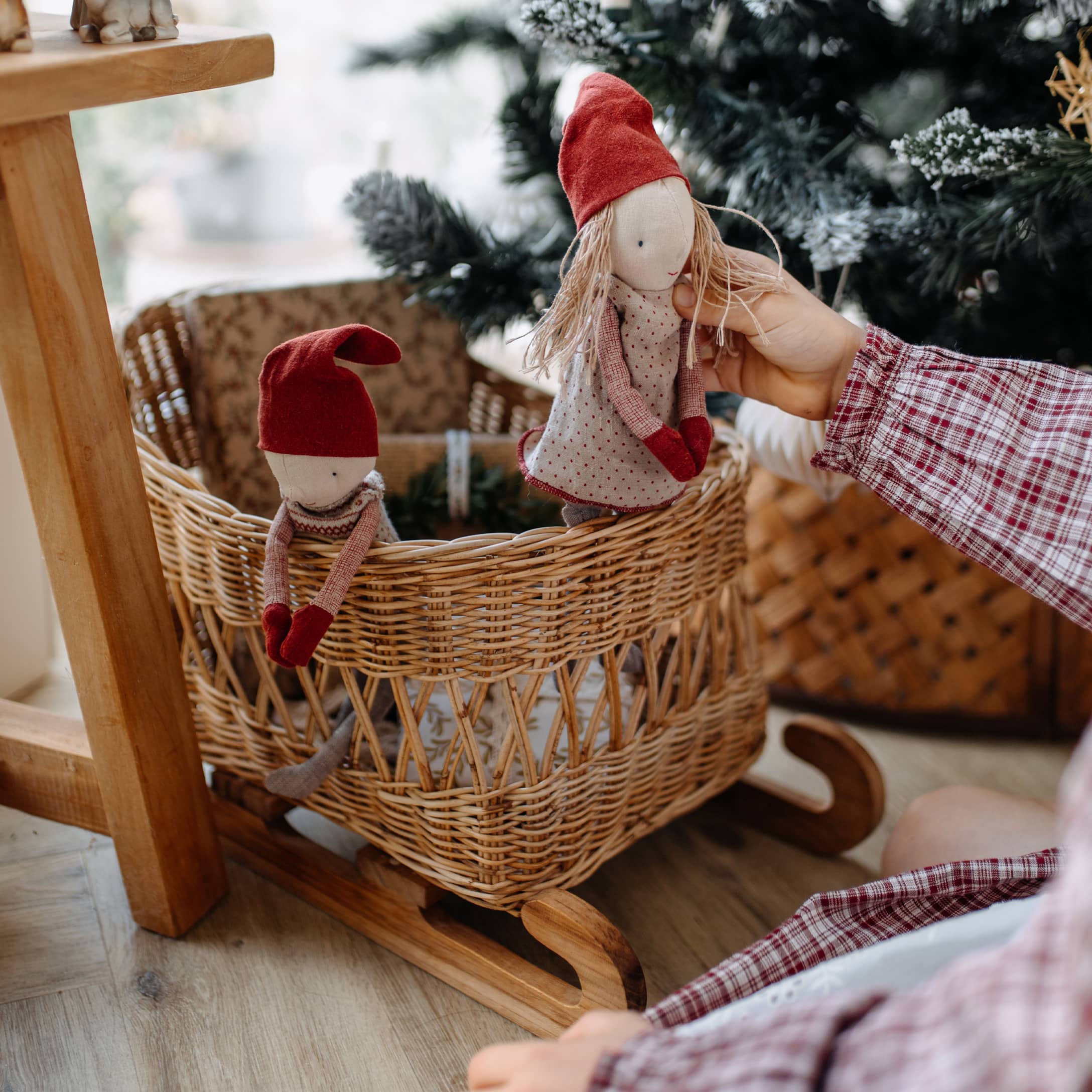 Mecedora de madera con cesta de mimbre y dos muñecas con gorros rojos, decoración navideña