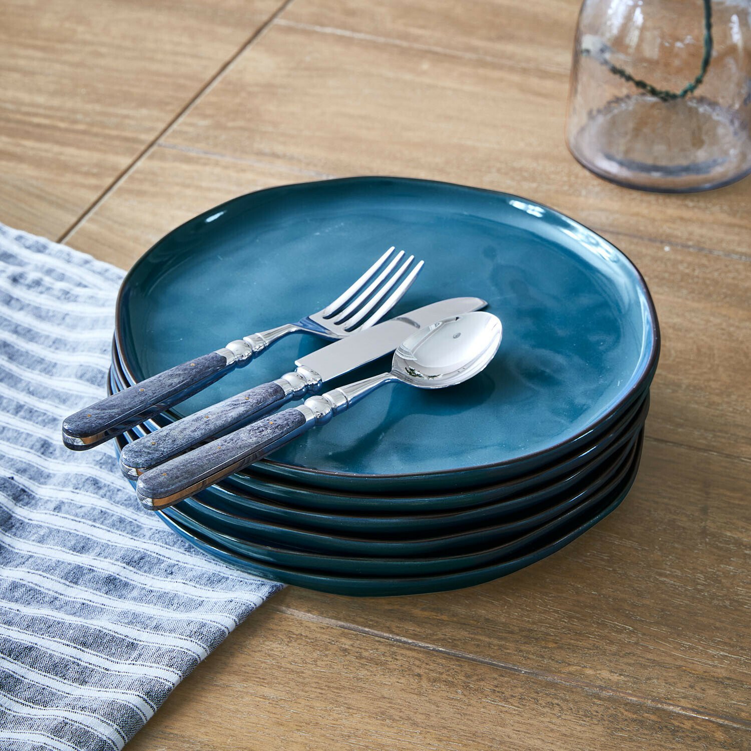 Set de 6 platos Biarré Conjunto de platos de cerámica azul con cubiertos metálicos y mangos de madera sobre mesa de madera