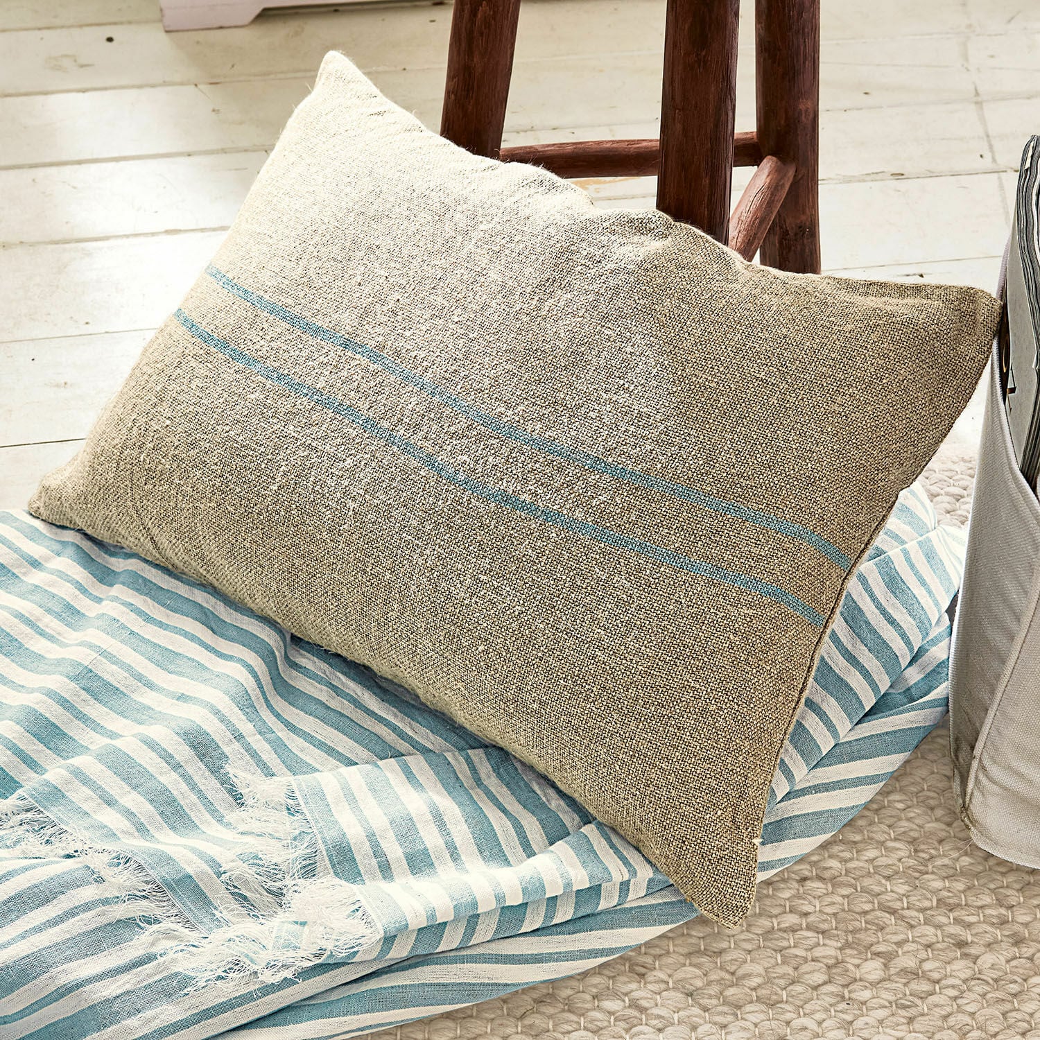 Funda de cojín Arrentès Cojín beige de lino con rayas azules sobre manta a rayas azul y blanca, decoración de interiores