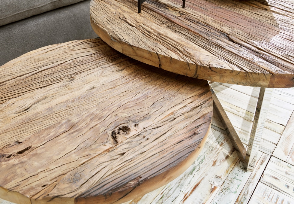 Dos mesas redondas de madera natural con textura visible y patas metálicas en estilo industrial