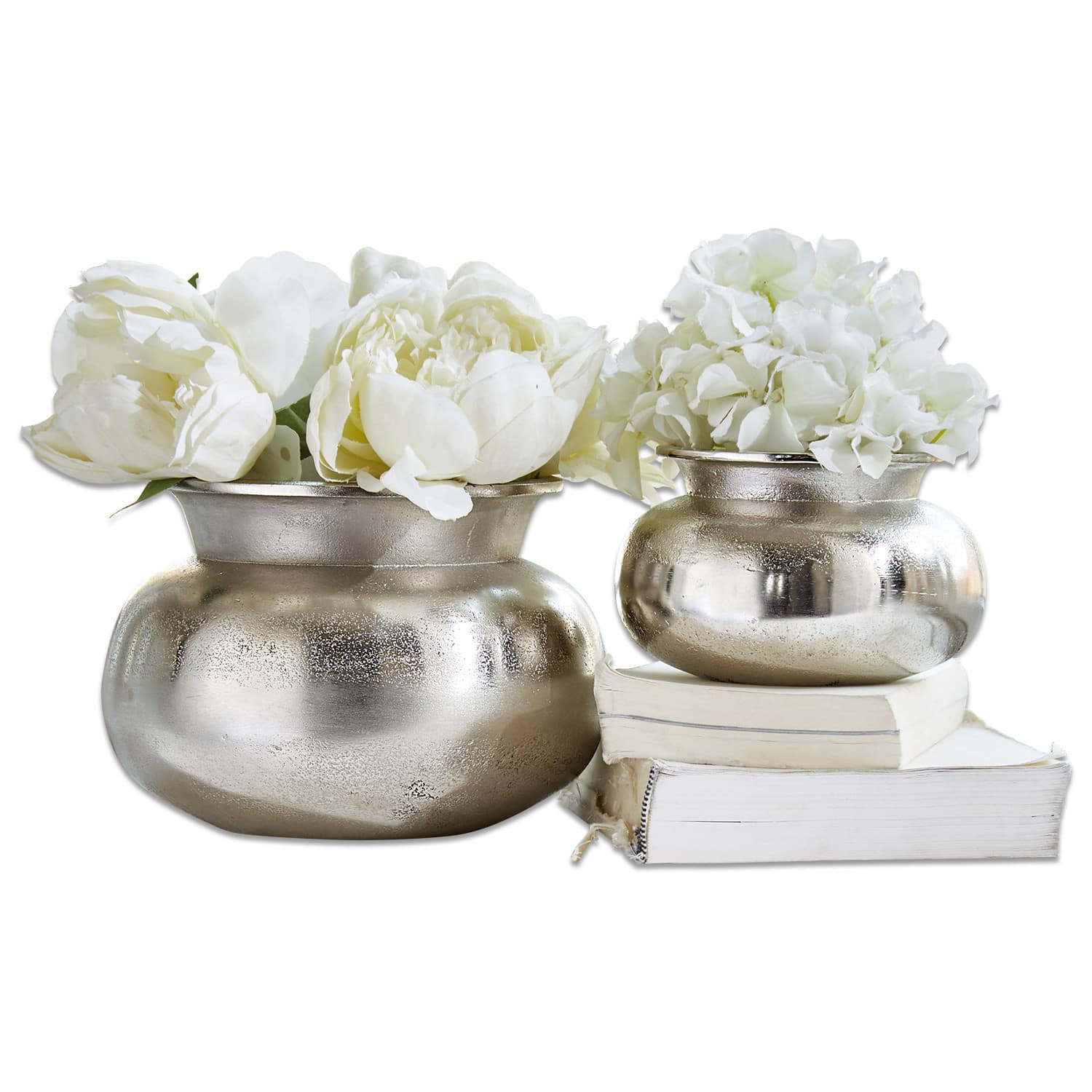 Set de 2 jarrones Clément Dos jarrones metálicos plateados con flores blancas sobre libros blancos, decoración elegante