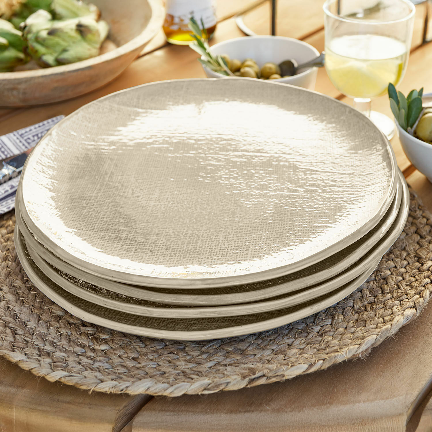 Set de 4 platos grandes Luganville Juego de platos de cerámica beige con textura sobre un salvamanteles trenzado de madera