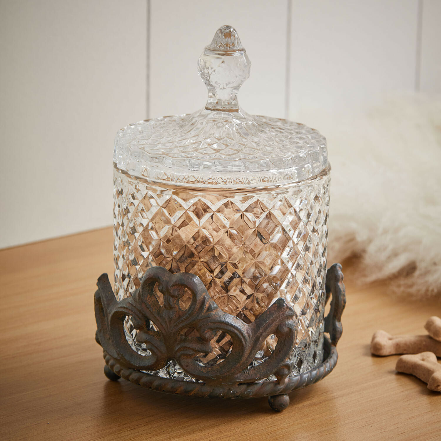 Tarro de cristal con soporte Kerynna Recipiente de cristal con tapa y base metálica decorativa sobre mesa de madera, decoración hogar