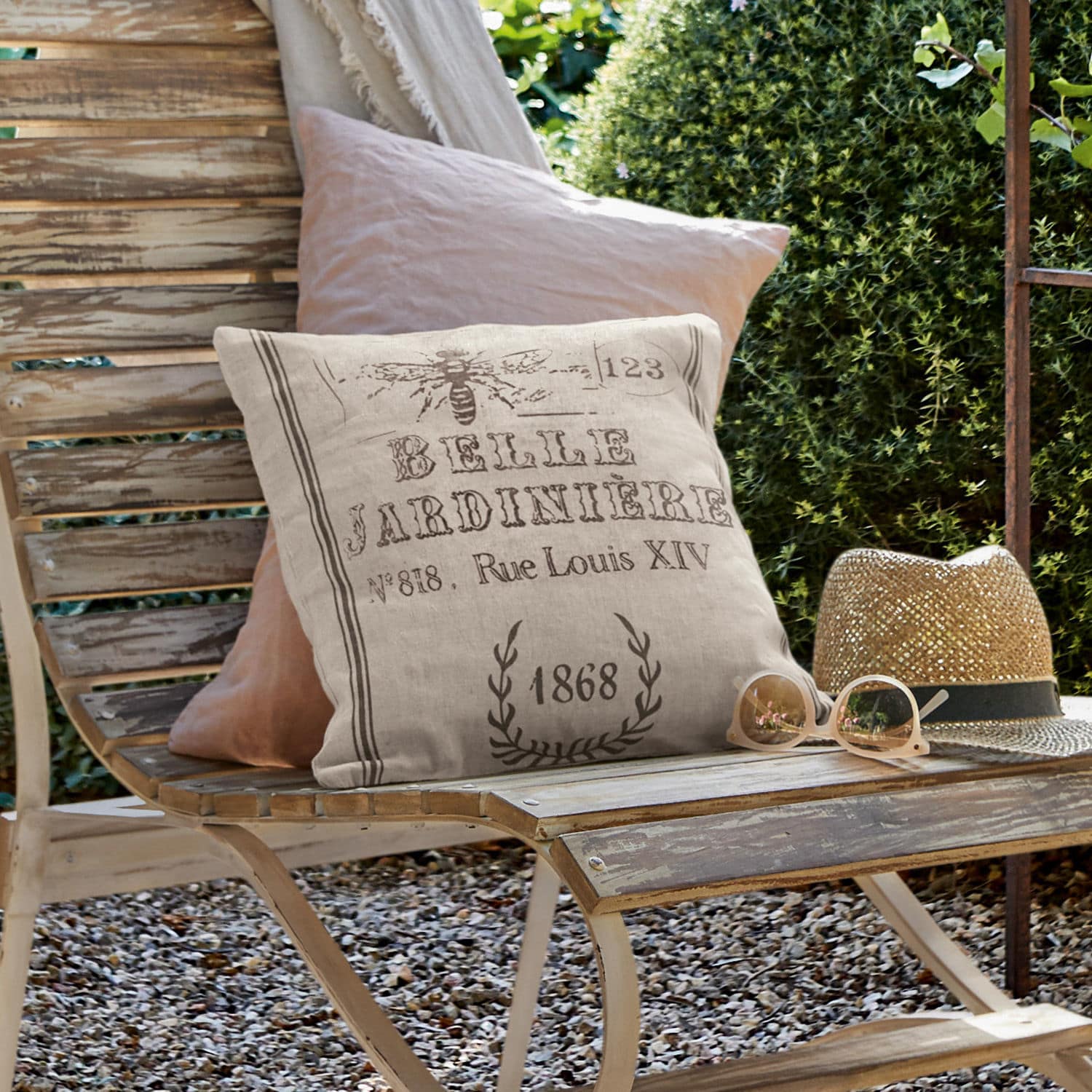 Funda de cojín Abelle Cojín decorativo de lino beige con estampado vintage sobre banco de madera en jardín exterior
