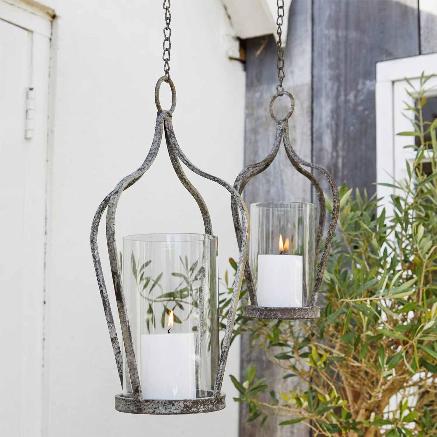 Faroles colgantes de metal envejecido con velas blancas y protección de vidrio para decoración de jardín