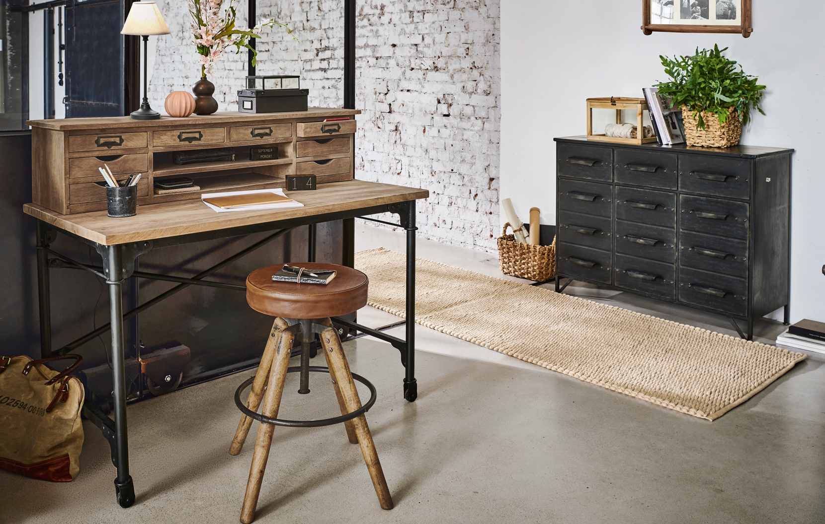 Escritorio industrial de madera y metal con múltiples cajones y taburete de cuero vintage en interior moderno