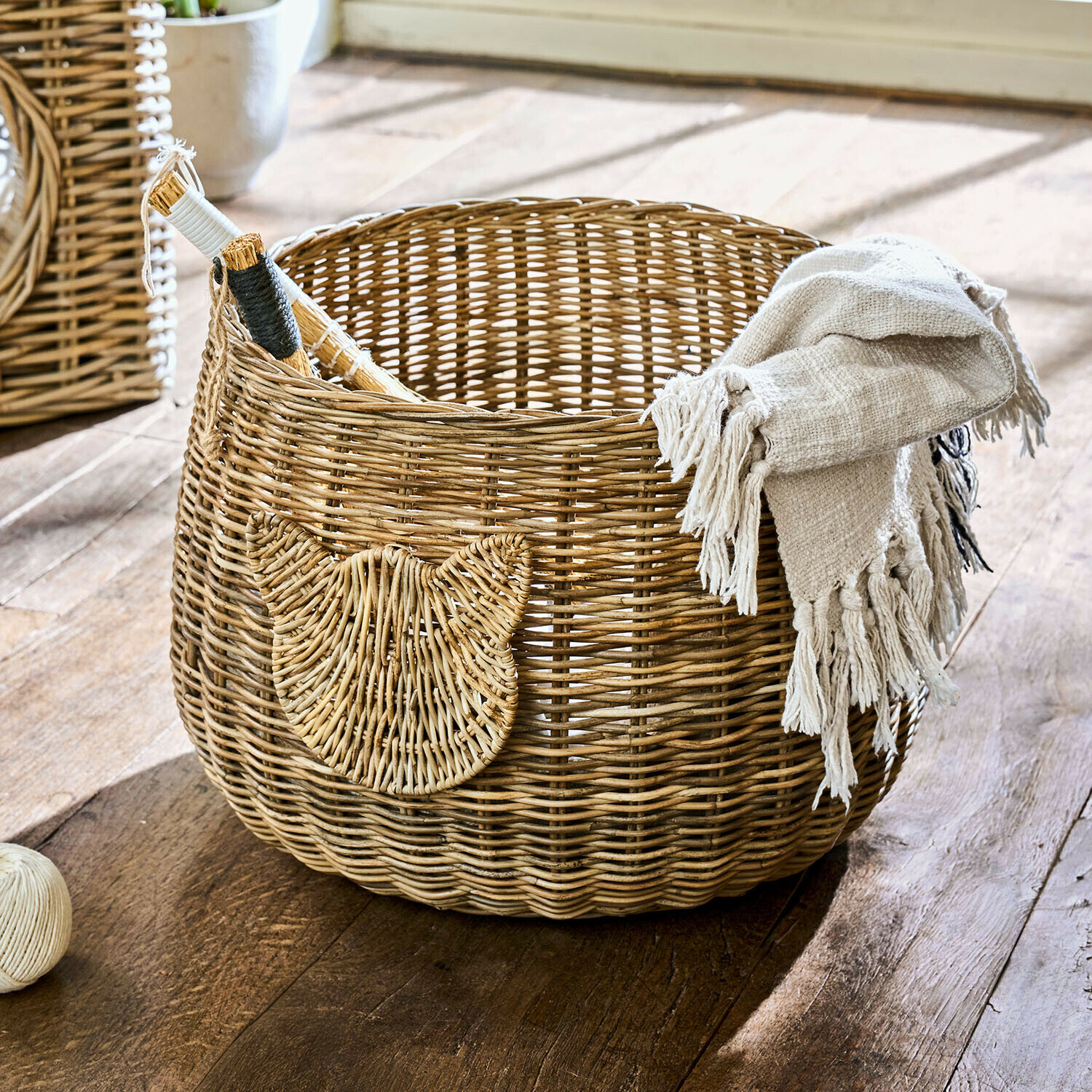 Cesta redonda de ratán natural con adorno de cabeza de gato y manta beige
