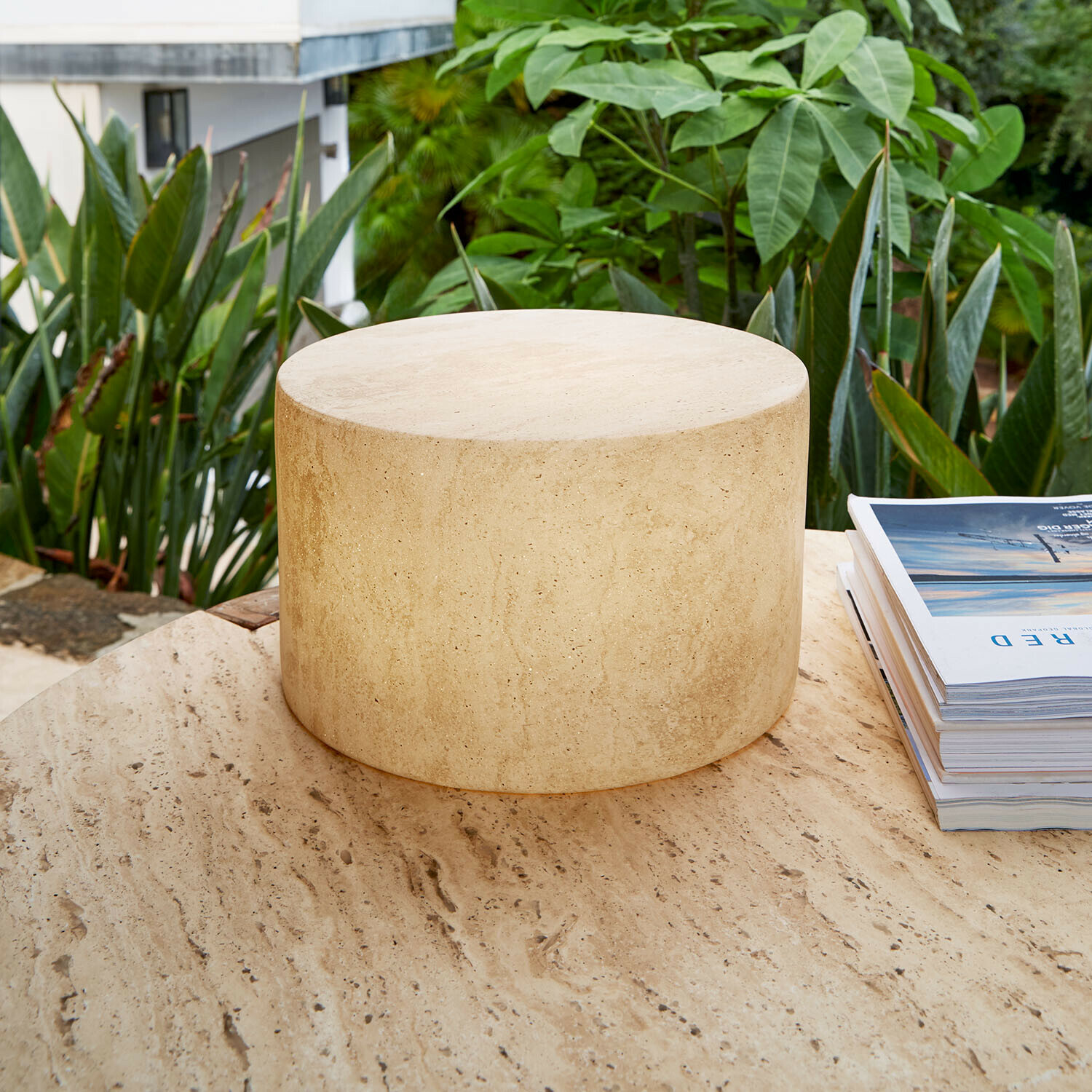 Lámpara LED recargable Marévos Mesa redonda de travertino beige en terraza con plantas verdes, piedra natural