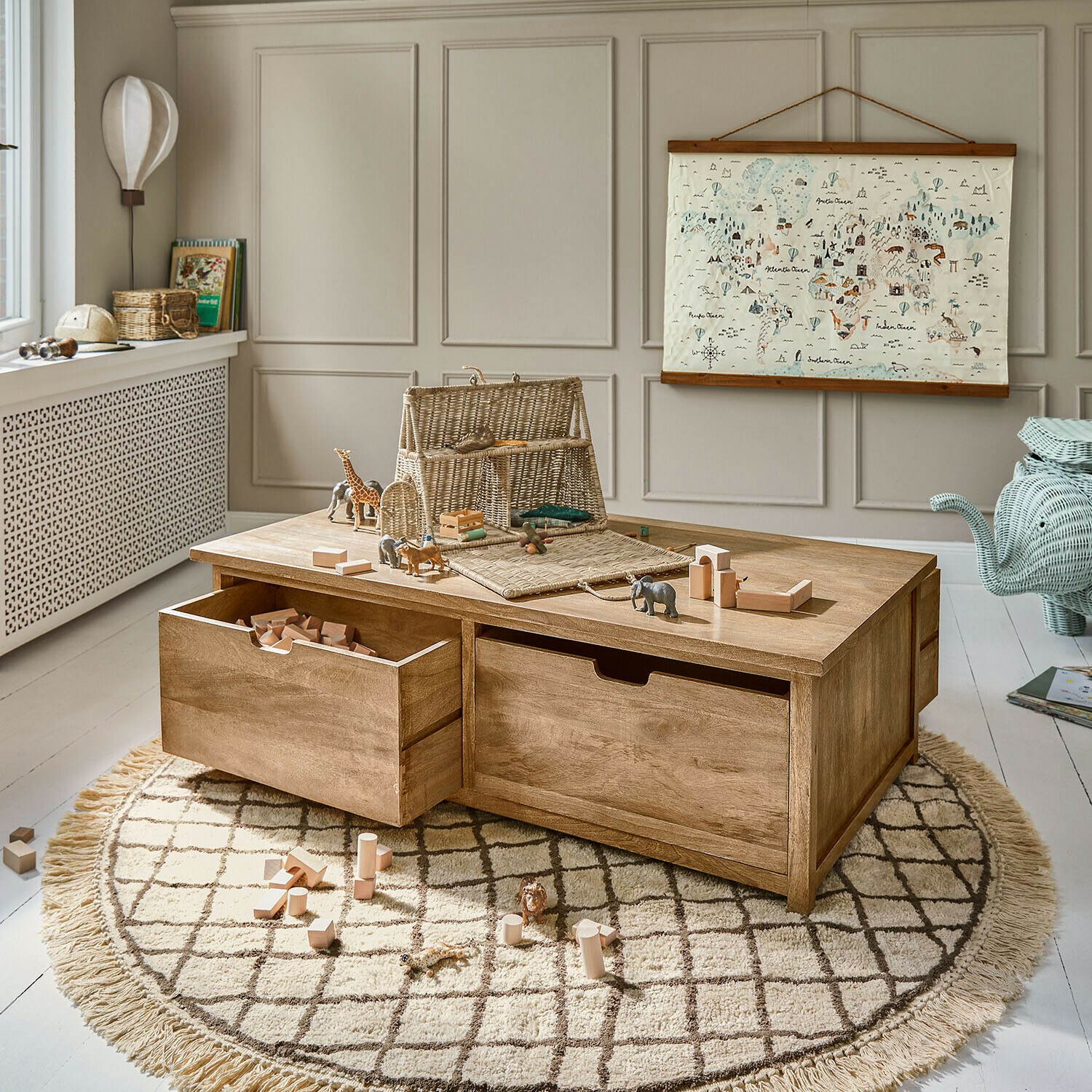 Mesa de juego de madera con cajones y bloques de madera sobre alfombra redonda en habitación infantil