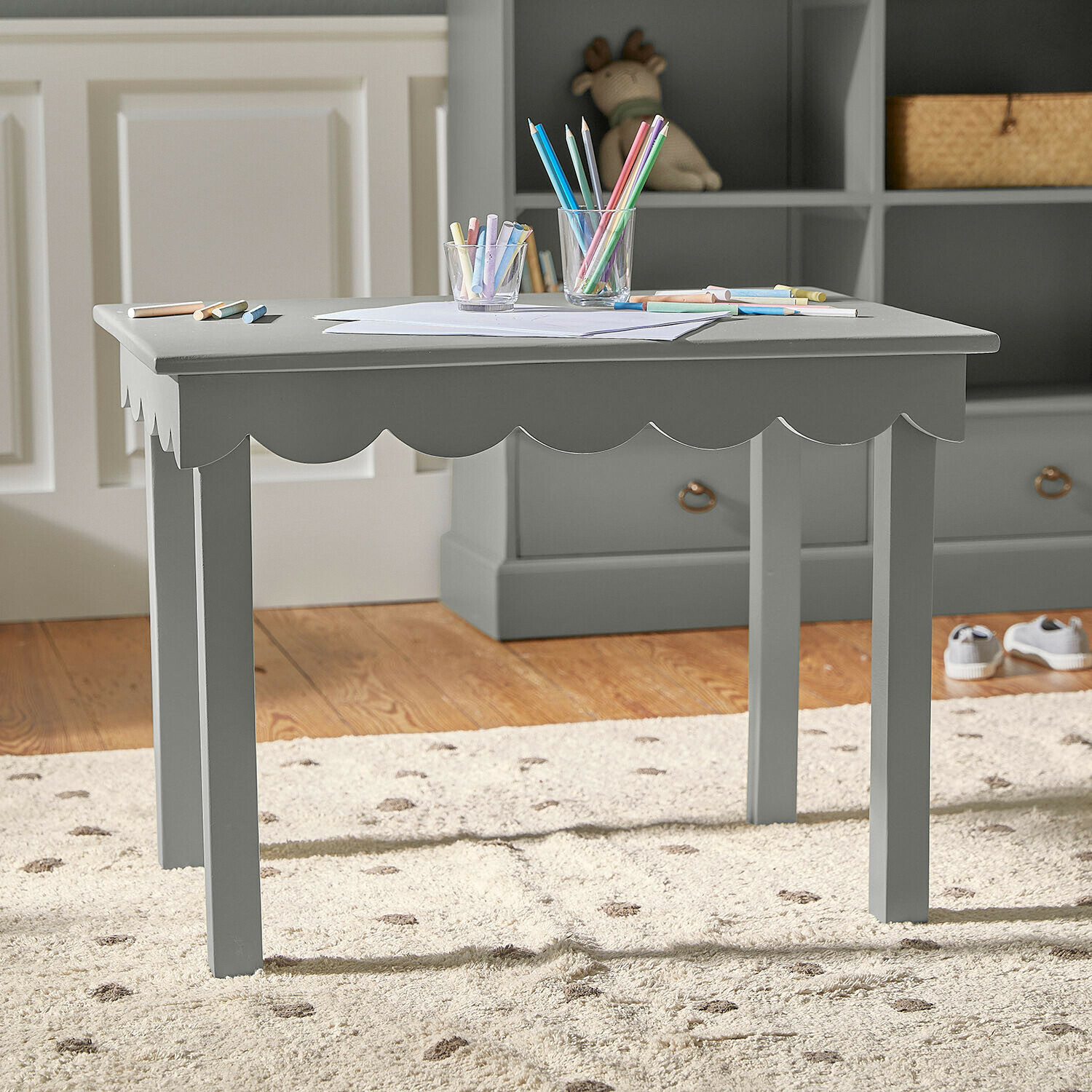 Mesa infantil de madera verde con borde ondulado y lápices de colores sobre la superficie para dibujar