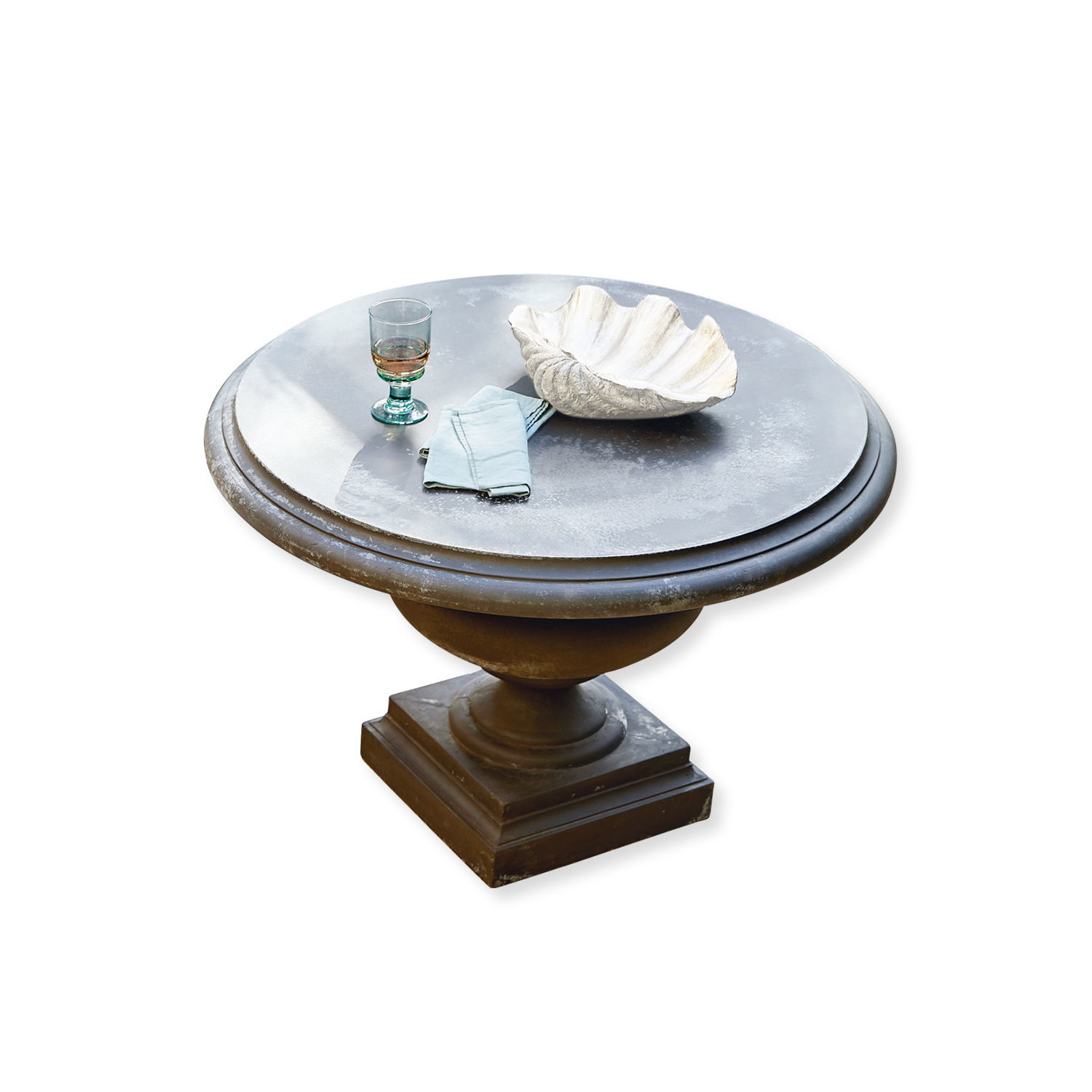Mesa redonda gris Monterey con base metálica, decorada con vaso y concha