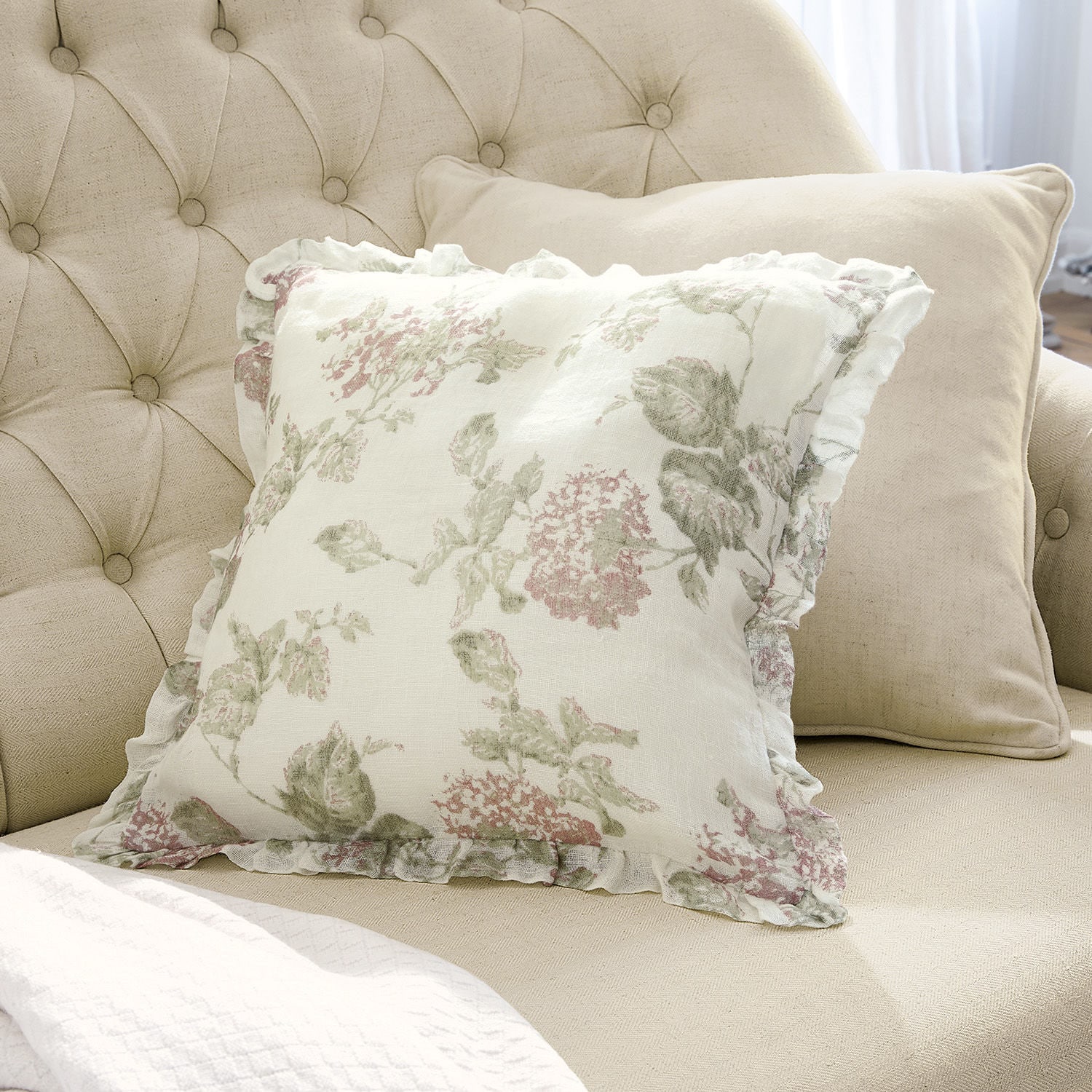 Sofá beige con dos cojines, uno con estampado floral y volante, algodón, decoración de interiores