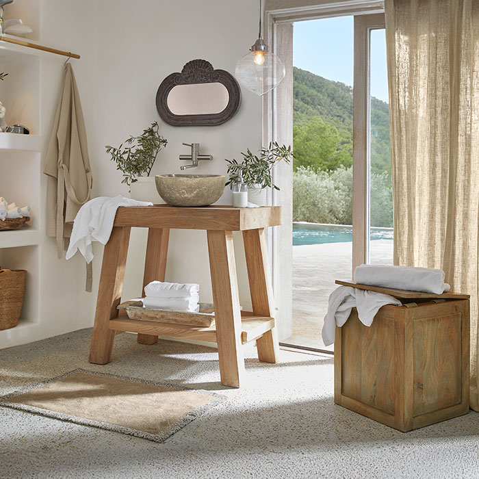 Baño con mueble de madera y lavabo de piedra, colores naturales y plantas decorativas