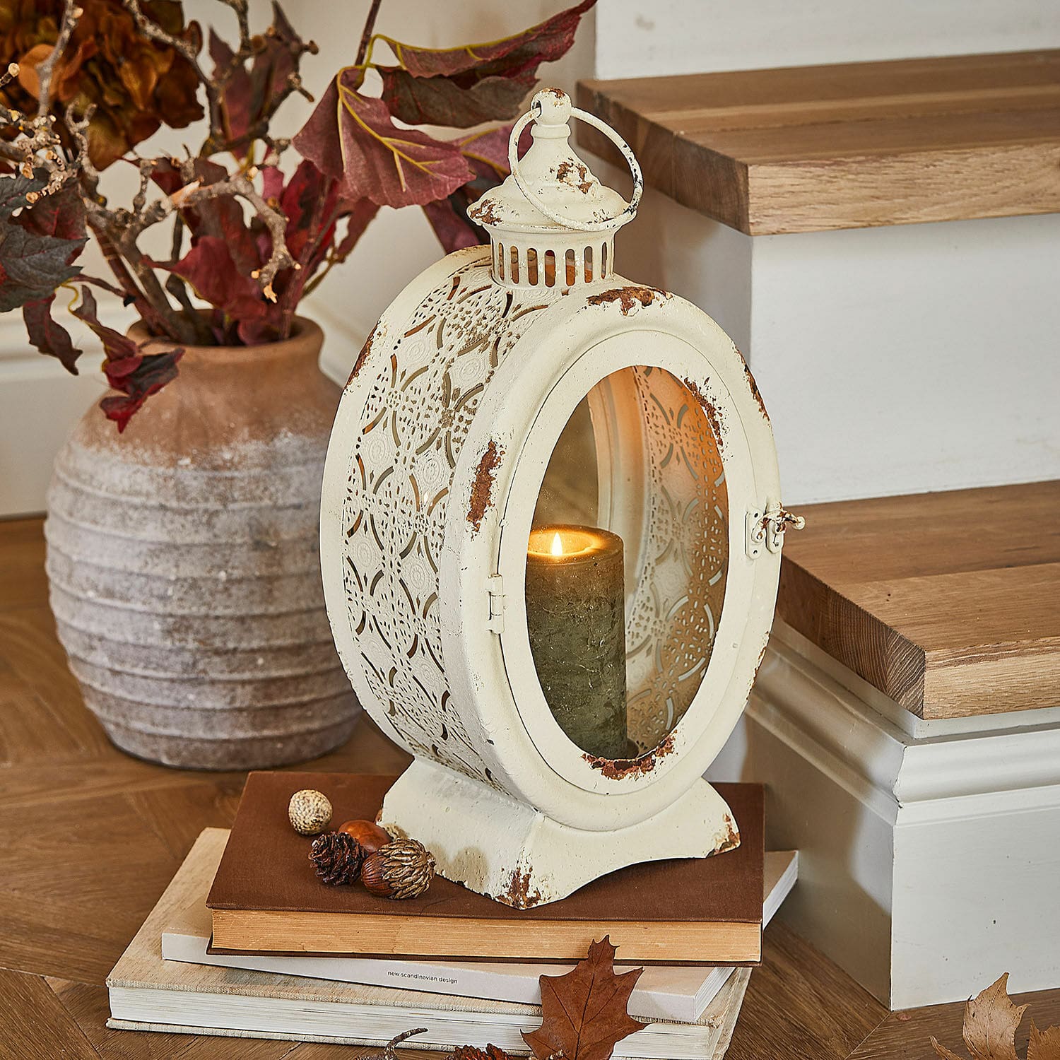 Farol Sublimelle Linterna metálica vintage color crema con vela encendida y decoración otoñal sobre libros