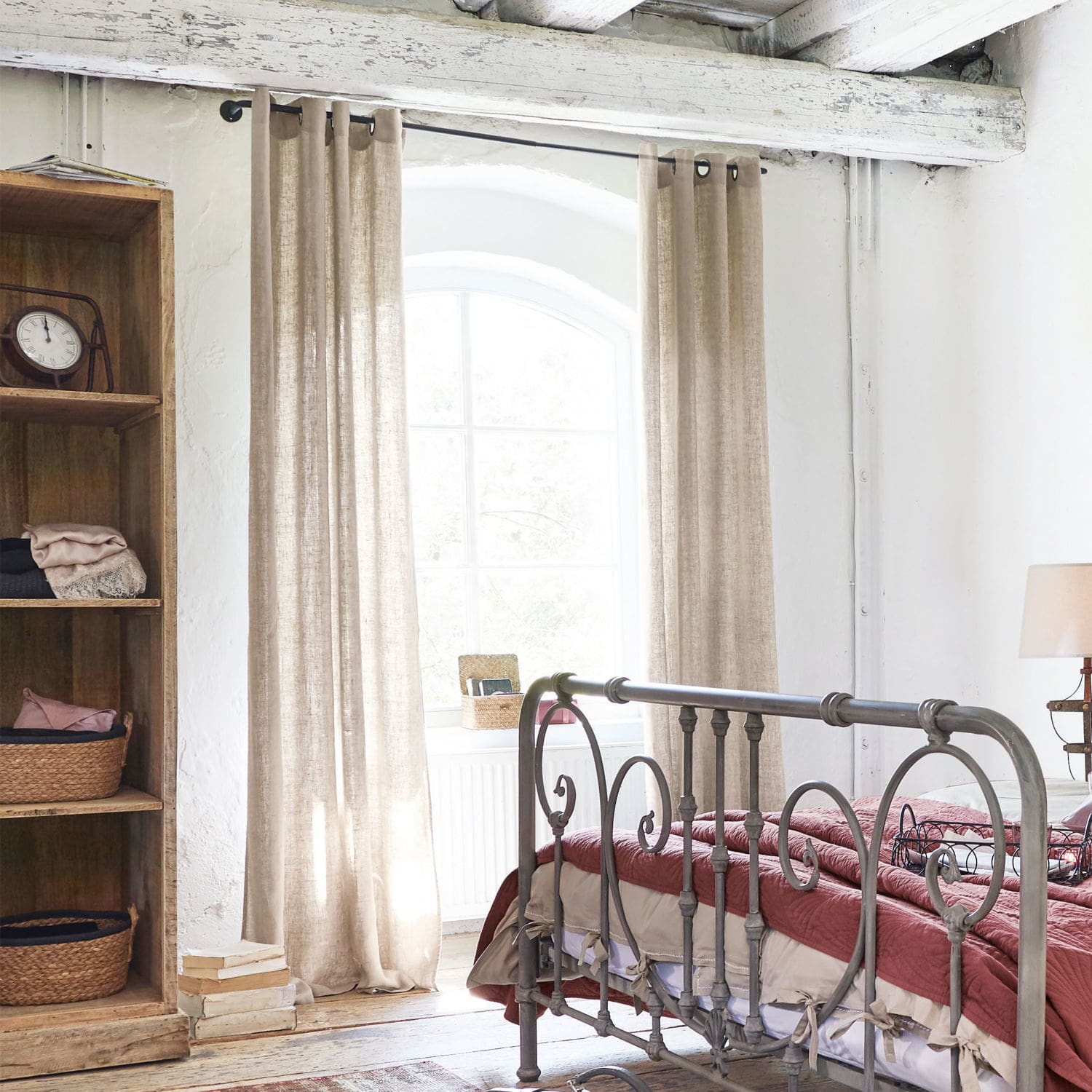 Dormitorio con cama de metal y cortinas beige de lino natural en estilo rústico