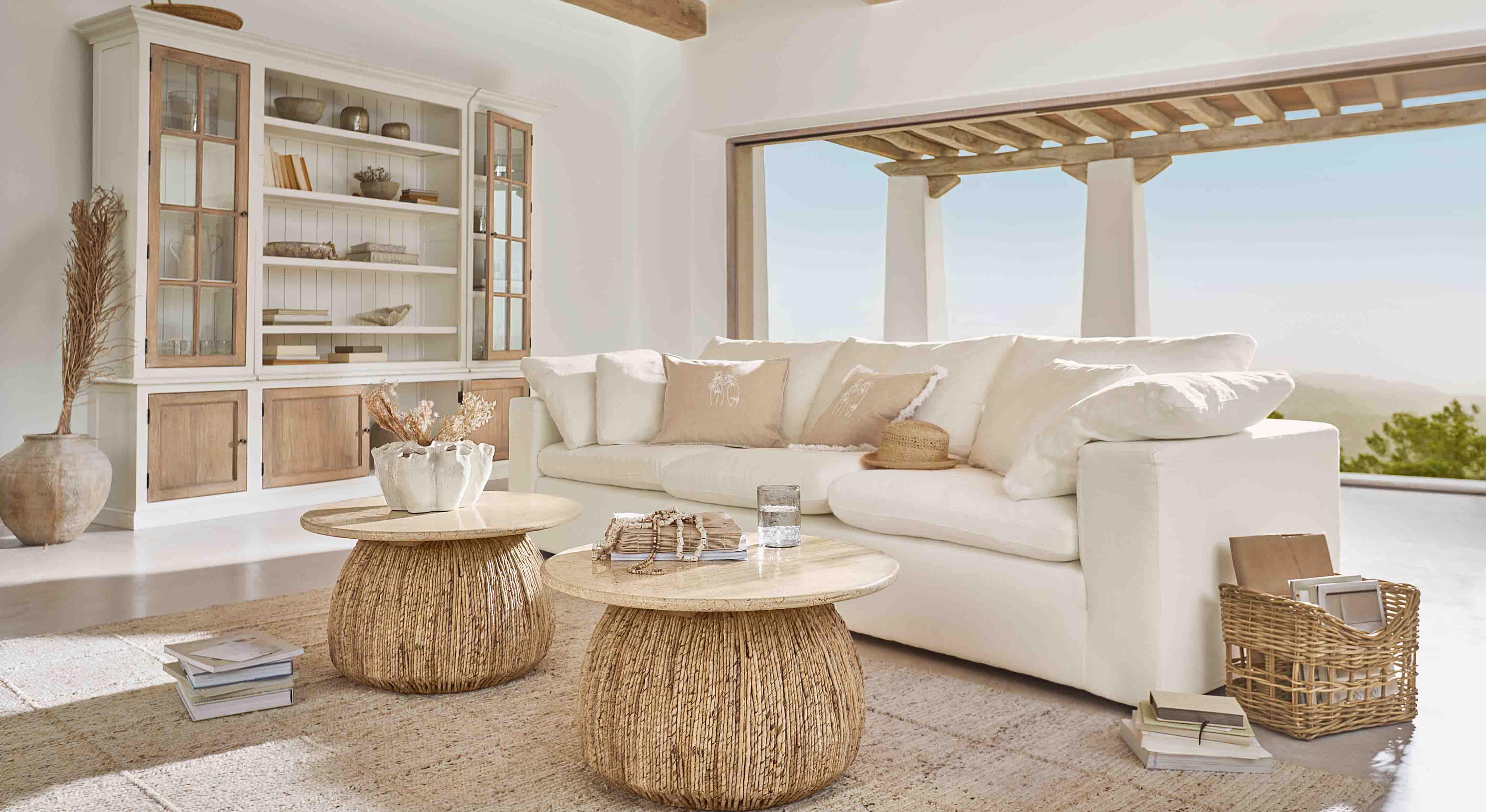 Sala acogedora con sofá blanco y dos mesas de centro redondas de madera natural y ratán
