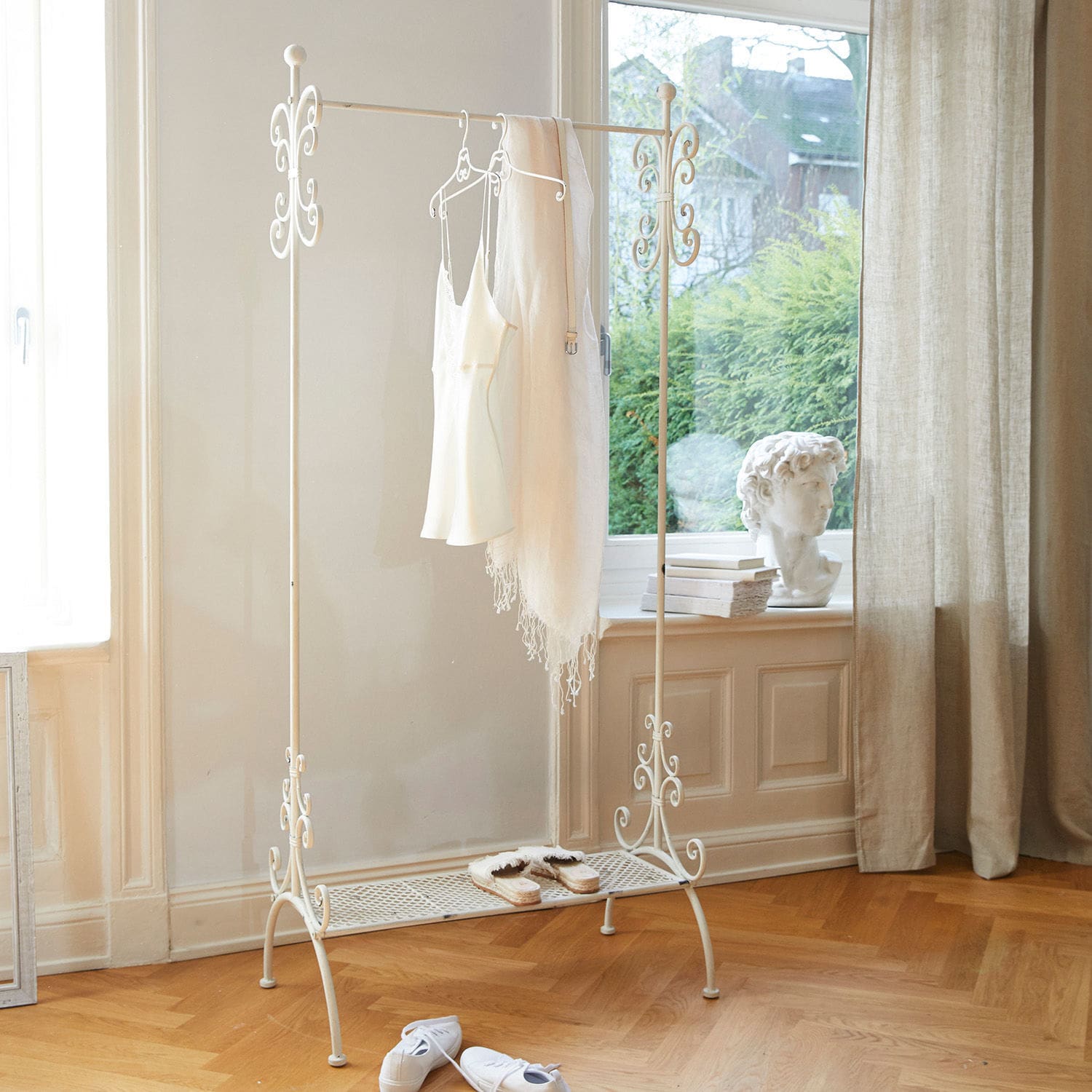 Perchero Épinay Perchero metálico blanco con detalles decorativos y estante para zapatos en habitación luminosa