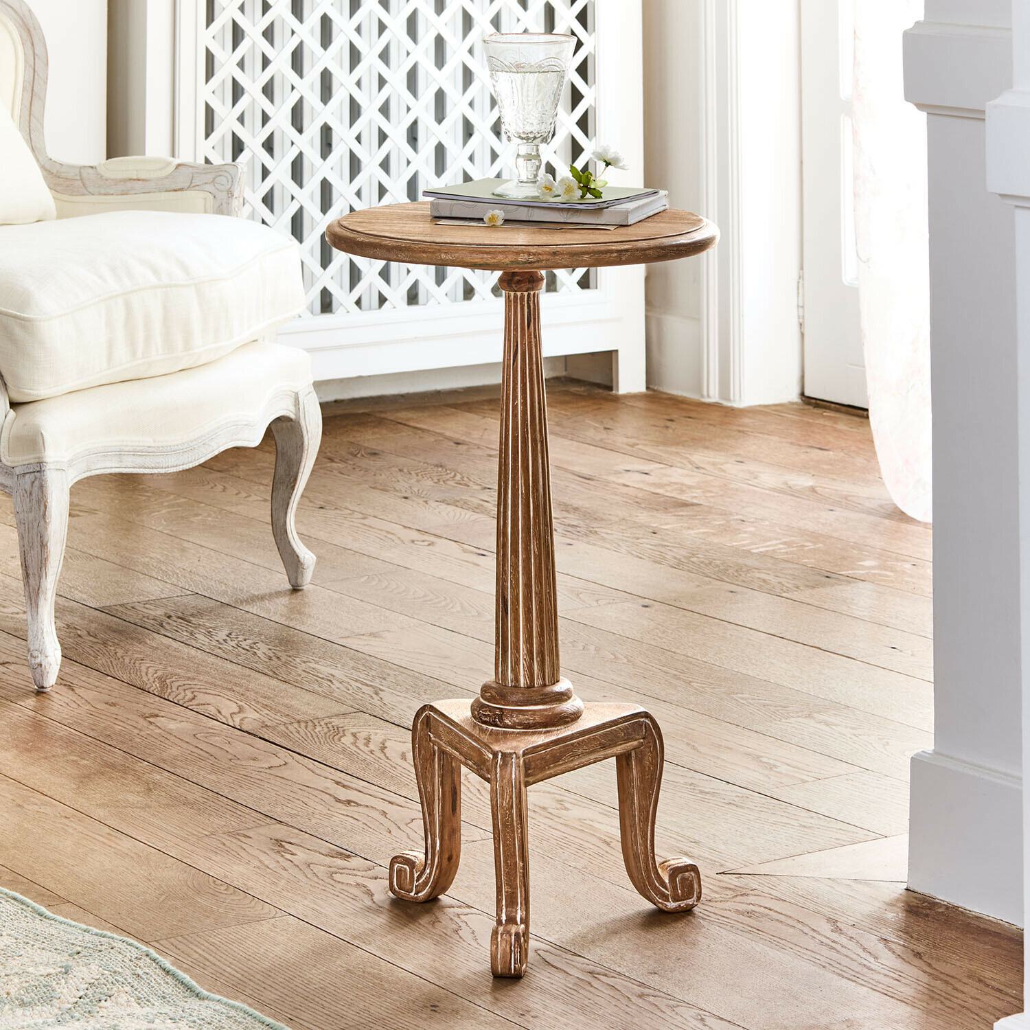 Mesa auxiliar Taviano Mesa auxiliar redonda de madera natural con patas decorativas de estilo vintage en sala luminosa