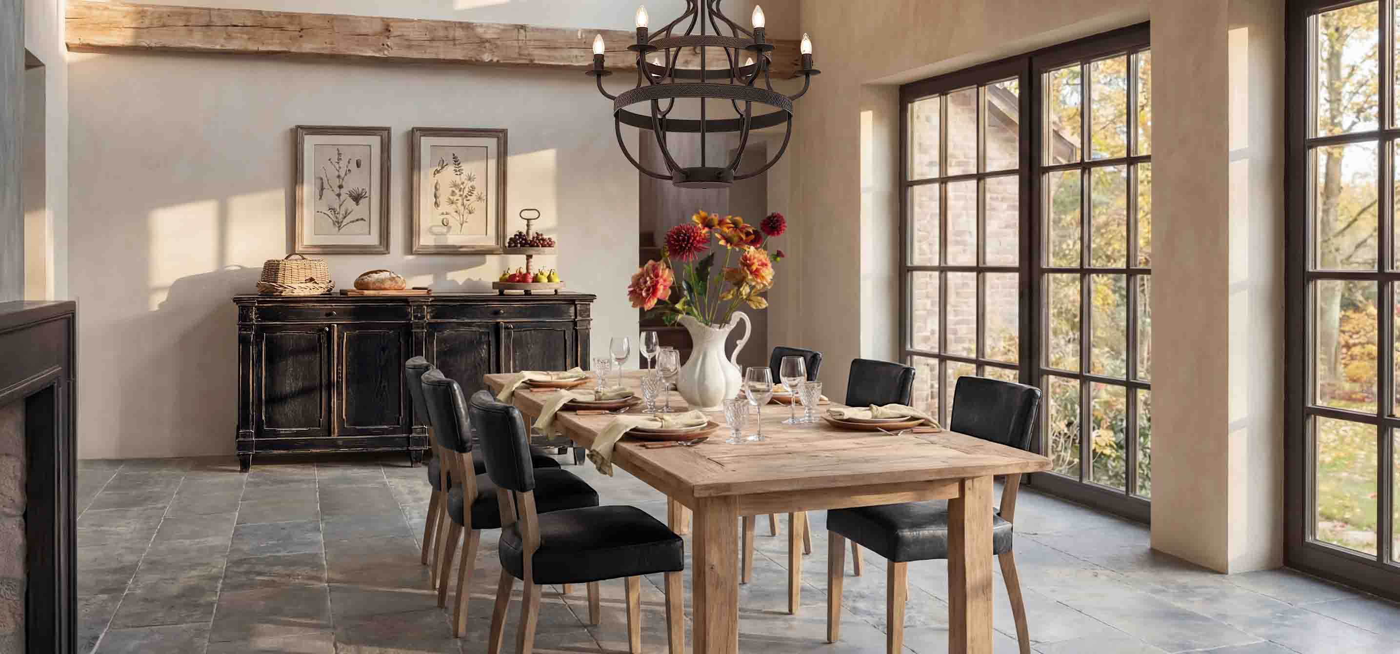 Comedor con mesa de madera, sillas negras y aparador rústico frente a grandes ventanas