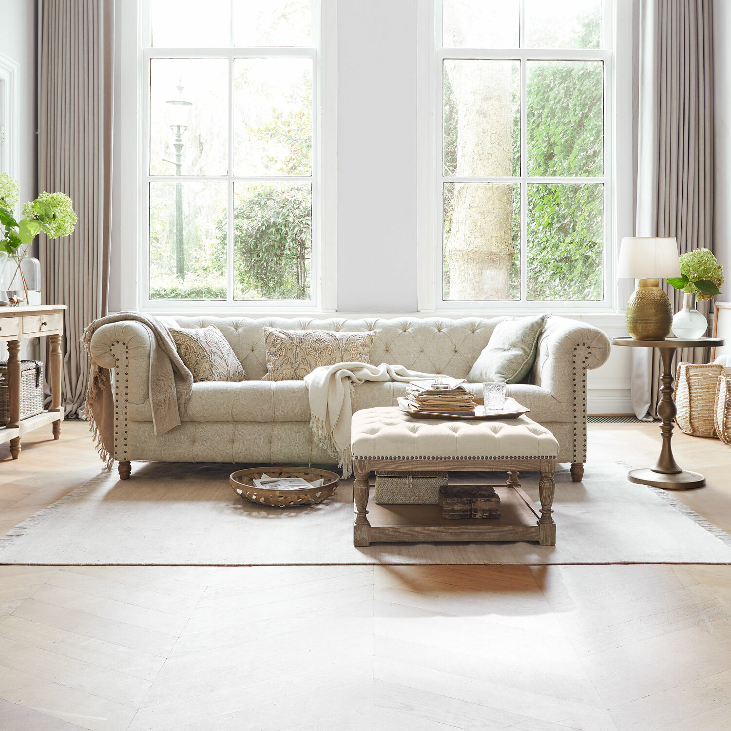 Sofá Parpeville Sofá beige tapizado en tela con cojines bordados y mesa de centro de madera en sala luminosa