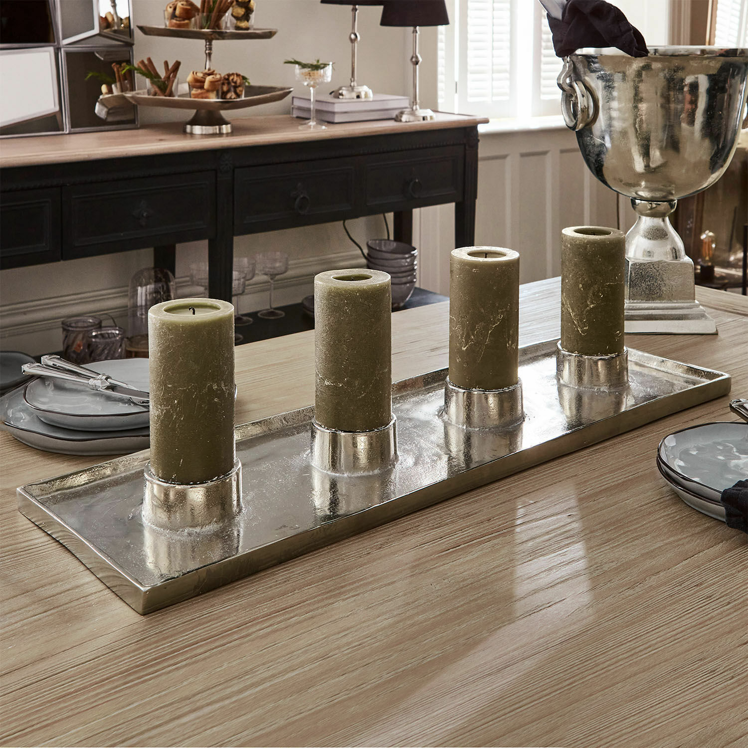 Conjunto de cuatro velas verdes sobre bandeja metálica plateada en mesa de madera en comedor