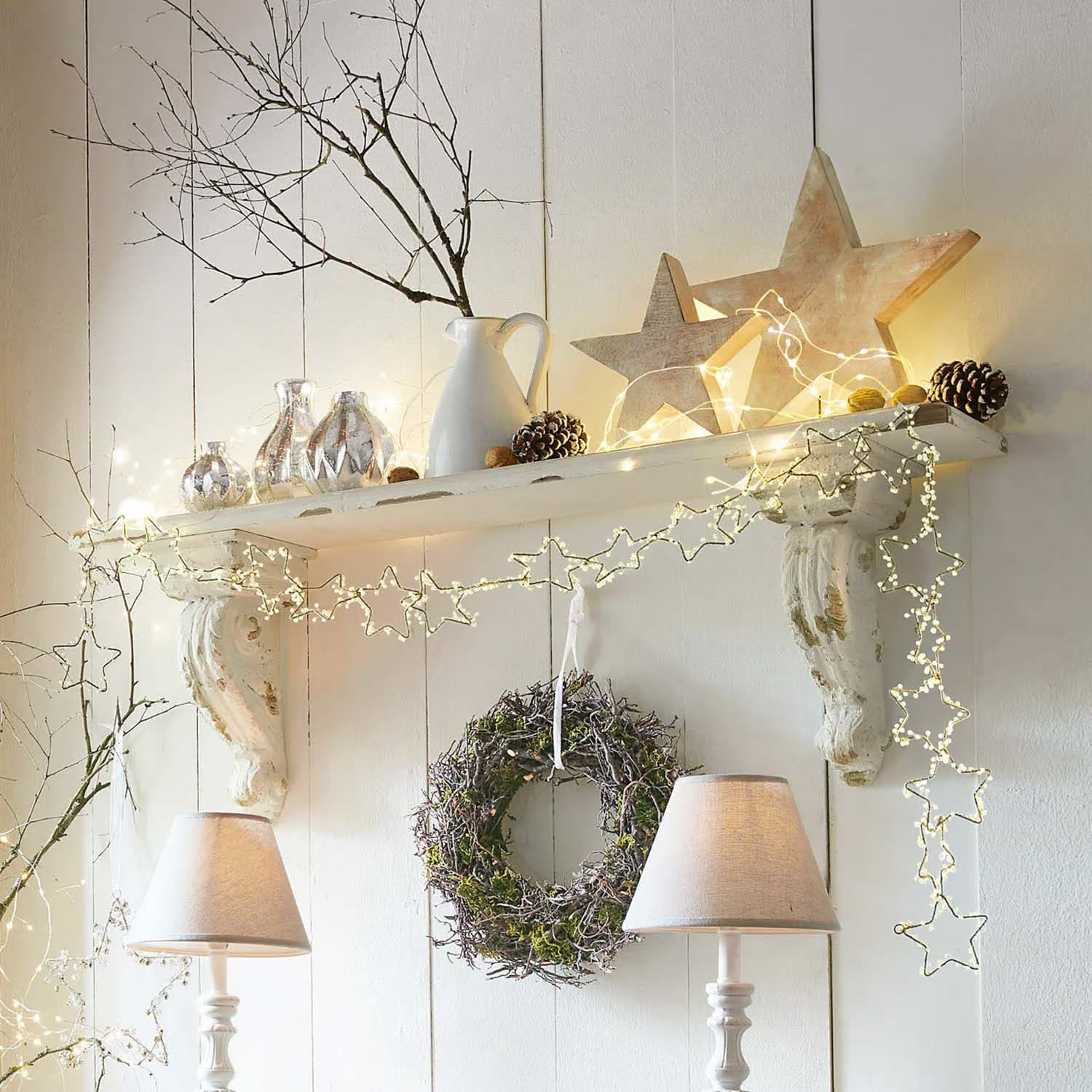 Estante decorativo blanco con luces en forma de estrellas, corona y lámparas de mesa en estilo rústico