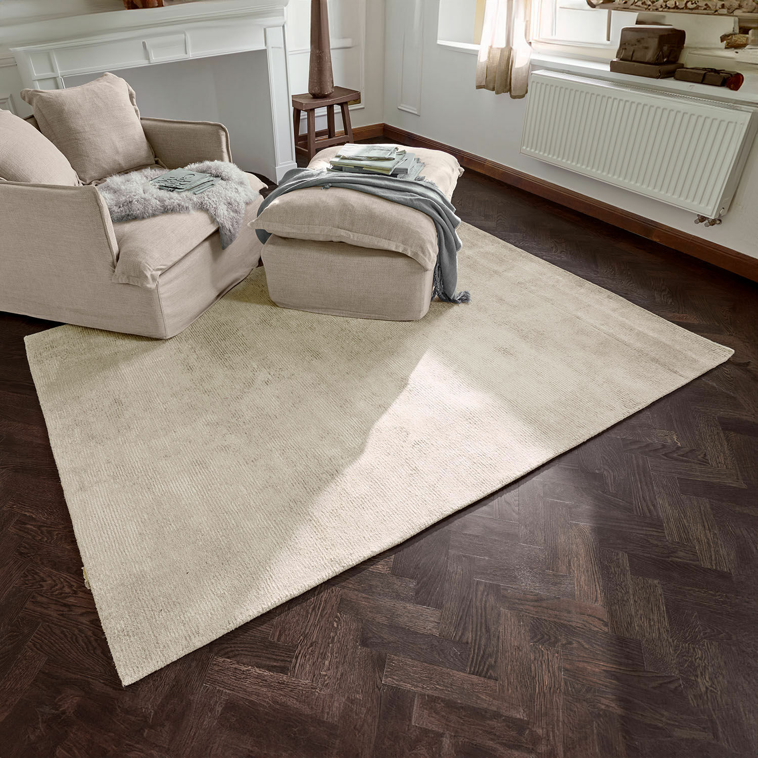 Alfombra Zaniyah Alfombra beige de material suave sobre suelo de madera oscura en sala acogedora