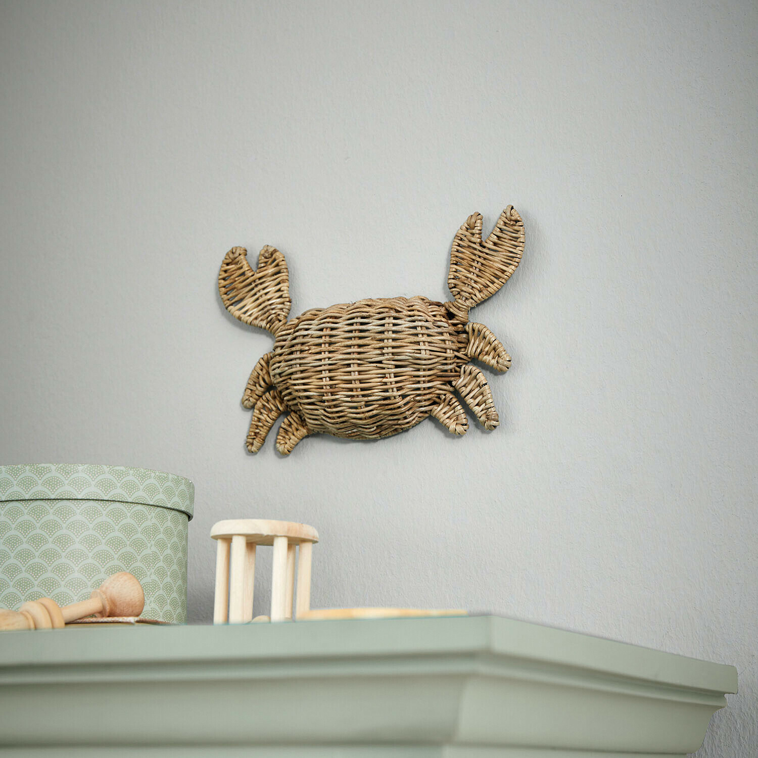 Decoración de pared en forma de cangrejo de mimbre natural sobre pared clara