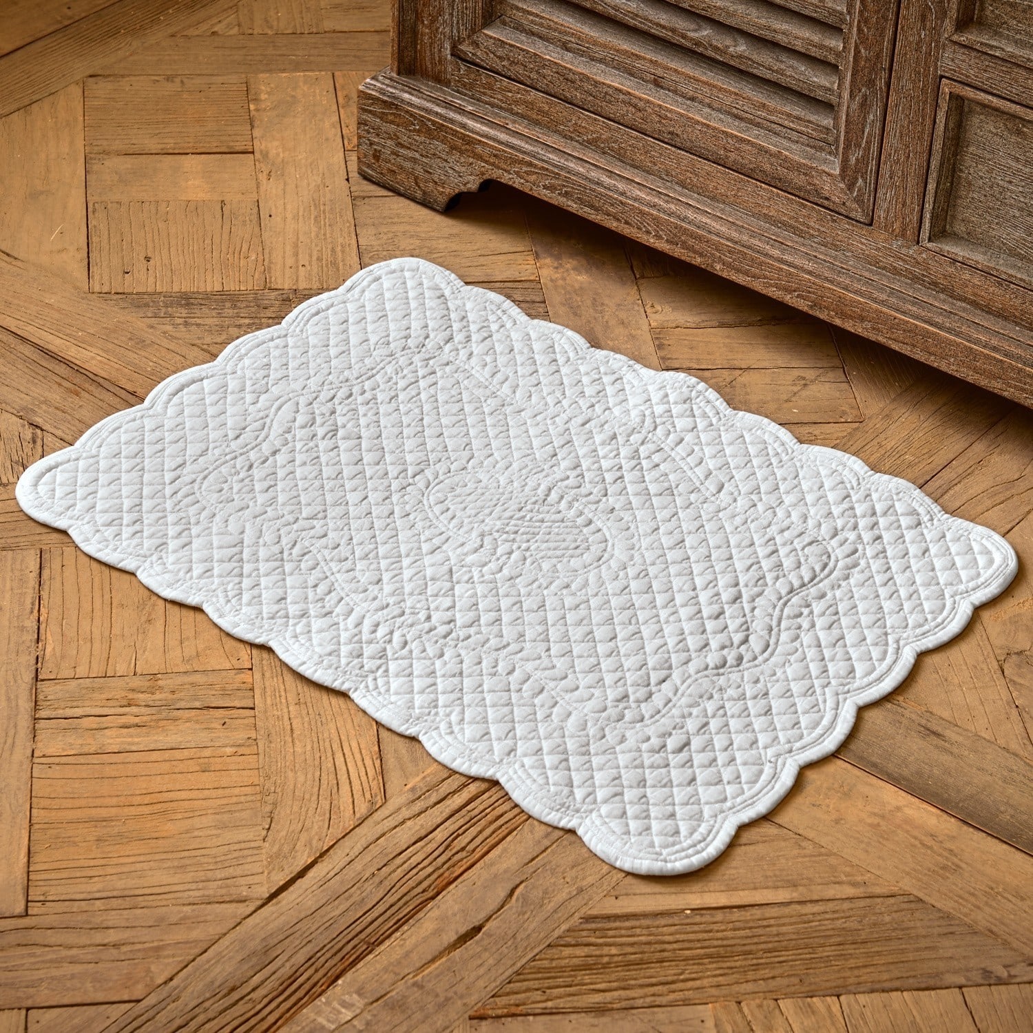 Alfombrilla de baño Meggie Alfombra blanca acolchada de algodón con diseño decorativo sobre suelo de madera, decoración interior