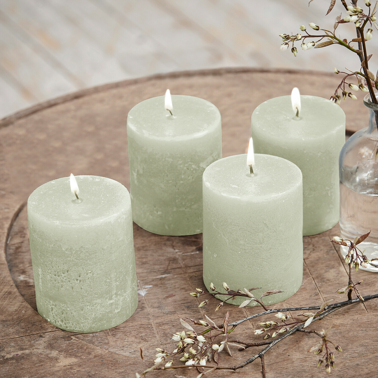 Set de 4 velas Virrans Conjunto de cuatro velas verdes de cera sobre bandeja de madera con ramas decorativas