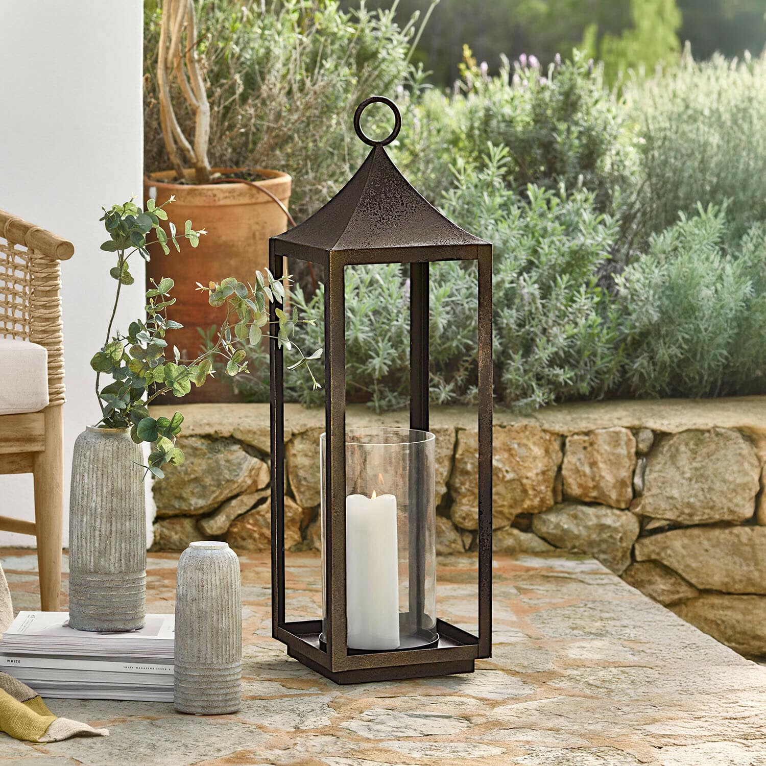 Farolillo Rosmaye Linterna de jardín de metal oxidado con vela blanca y protección de vidrio sobre mesa de piedra