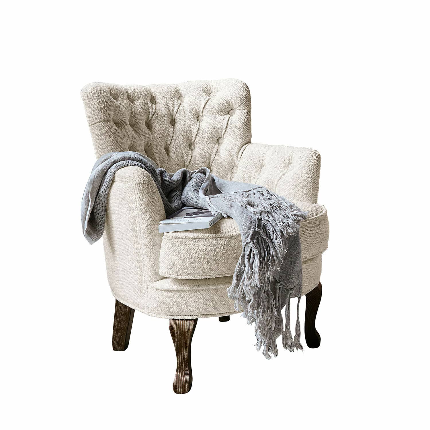Sillón Calgary Sillón beige de tela bouclé con patas de madera oscura, manta gris y libro encima
