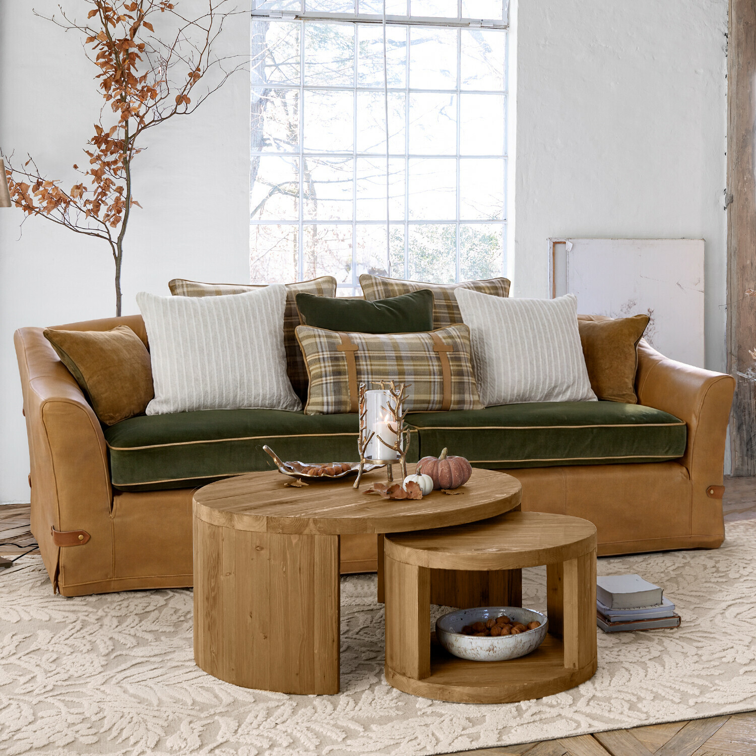 Sofa Halton Sofá de cuero marrón con asiento de terciopelo verde y cojines a cuadros y rayas en sala luminosa