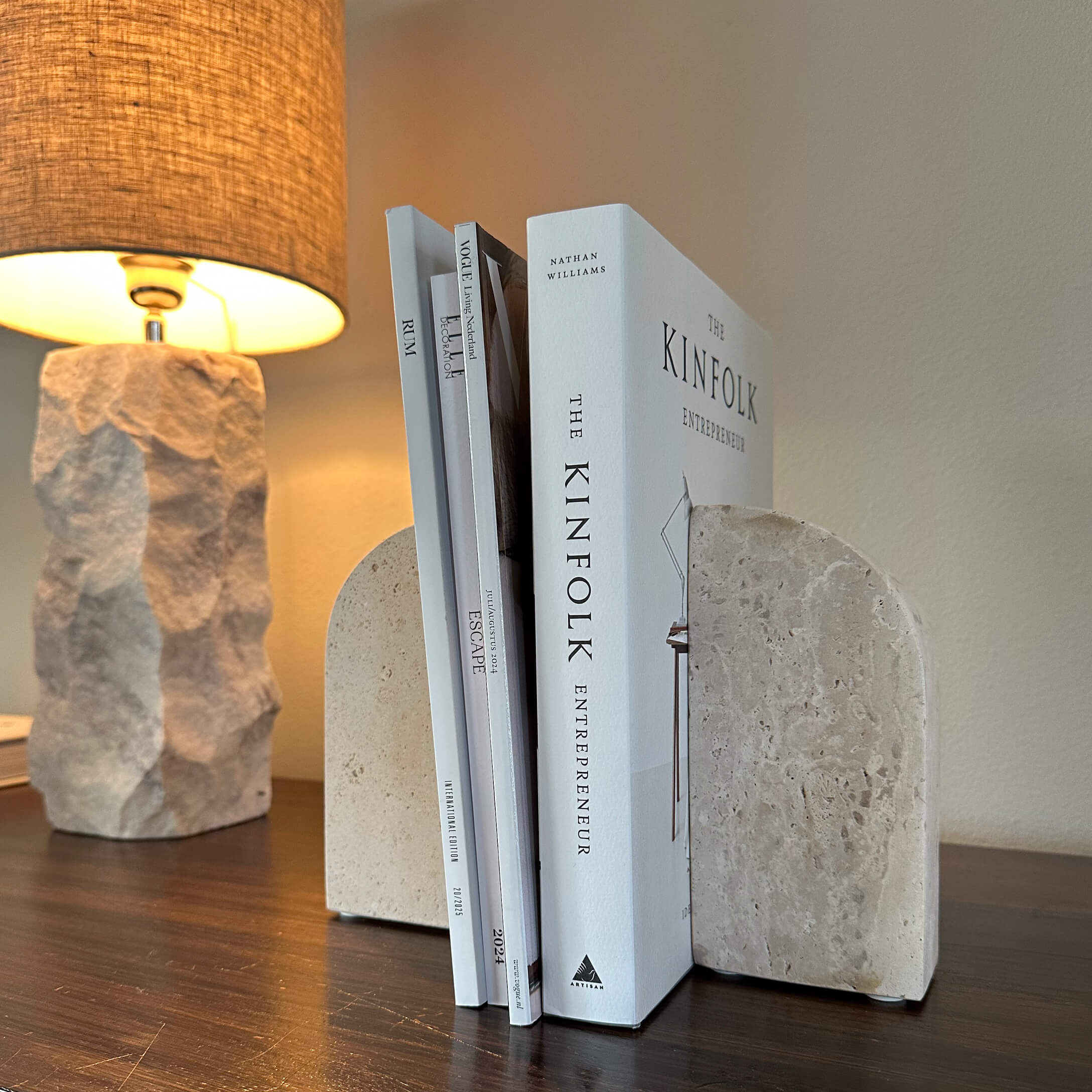 Sujetalibros de piedra beige sobre mesa de madera con lámpara encendida al fondo