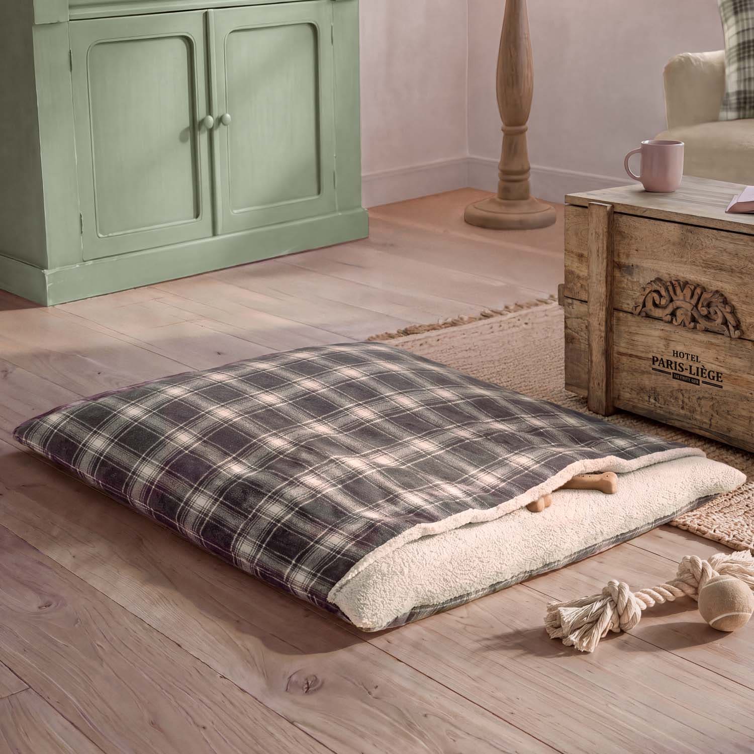 Cojín a cuadros con interior suave color crema sobre suelo de madera en ambiente acogedor