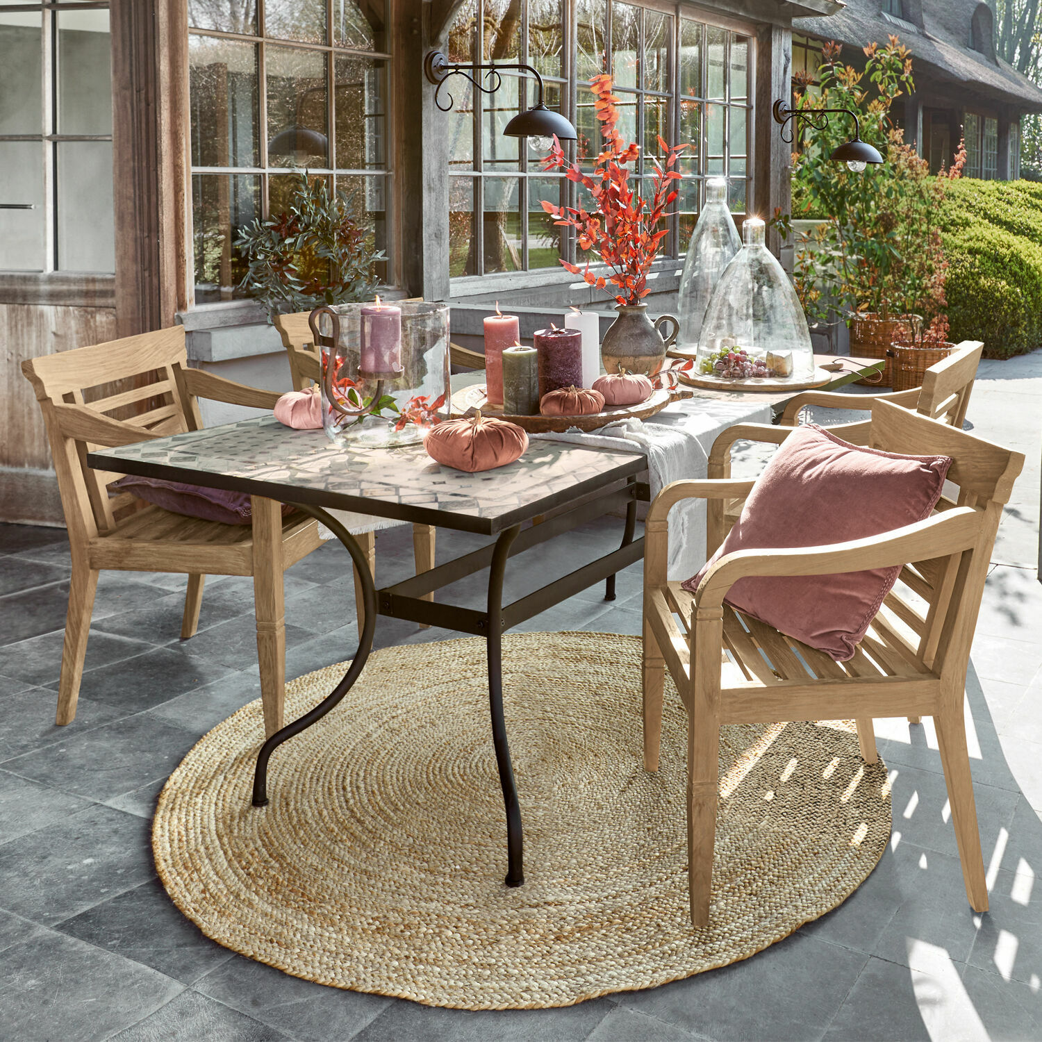 Mesa Labaroche Mesa con patas de metal y tablero de mosaico decorada con velas y cojines rosas en sillas de madera