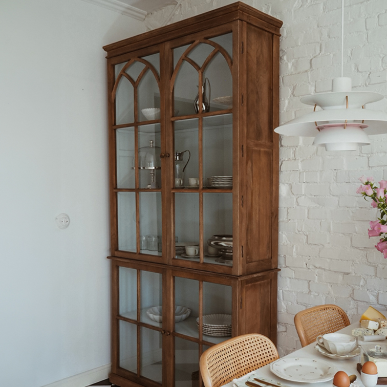 Vitrina de madera con puertas de cristal estilo vintage en comedor con pared de ladrillo blanco