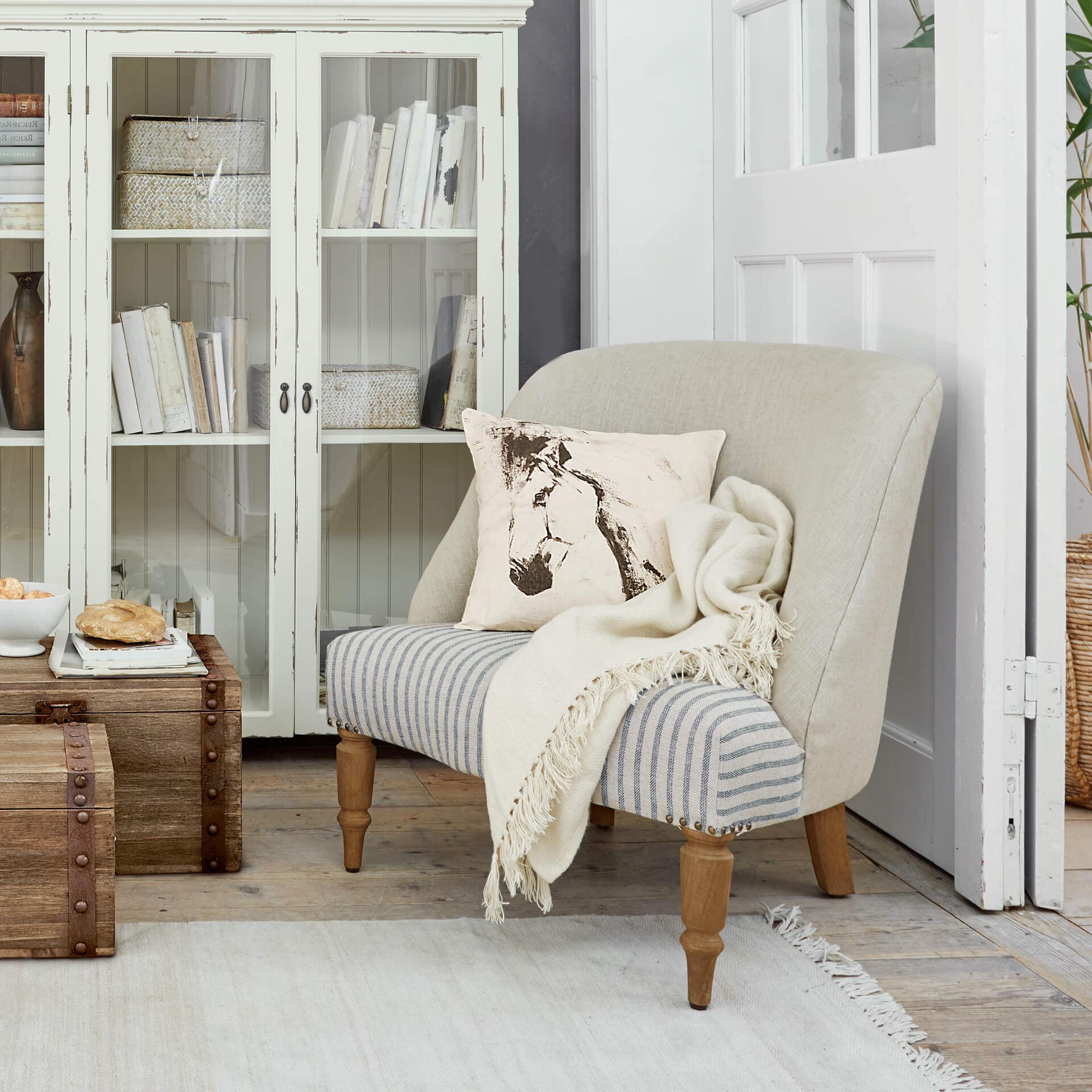 Sofá bicolor de madera y tela en beige y gris con cojín estampado de caballo y manta