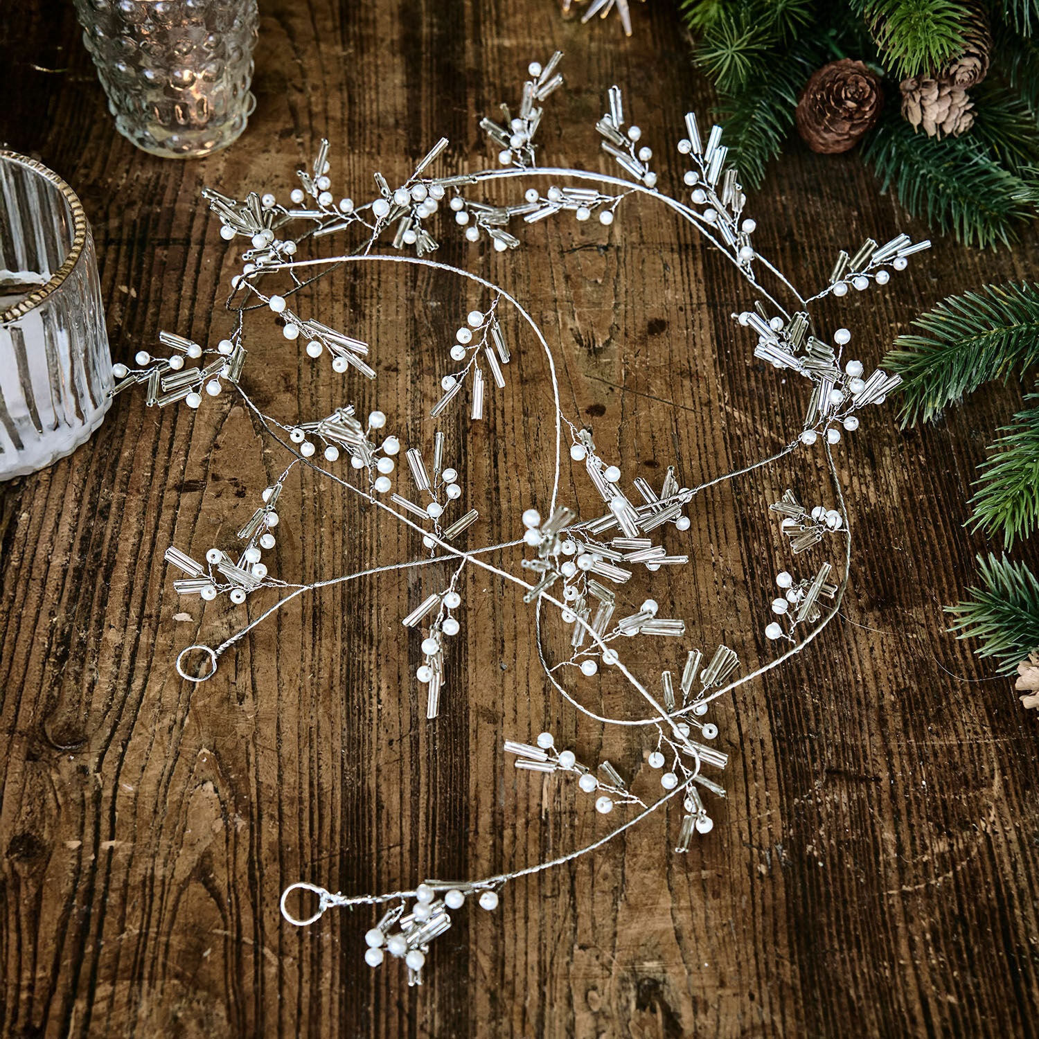 Guirnalda Hybern Cadena decorativa plateada con perlas blancas sobre mesa de madera, adorno navideño elegante