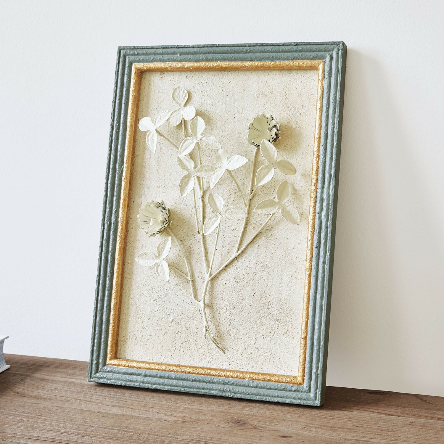 Cuadro Rivolenne Cuadro decorativo con relieve floral en marco verde y dorado sobre mesa de madera