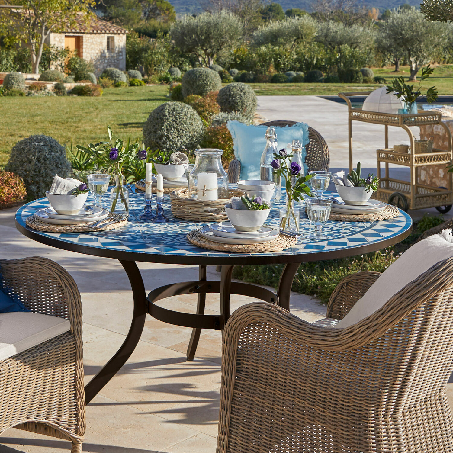 Mesa Jennarton Mesa de jardín redonda con tablero de mosaico azul y blanco y sillas de mimbre en la terraza
