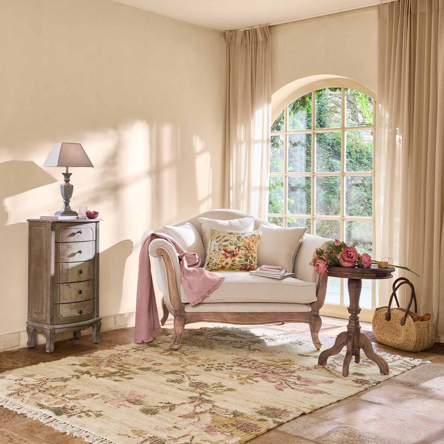 Sillón acogedor de madera clara y tela crema con cojines y manta rosa en sala luminosa