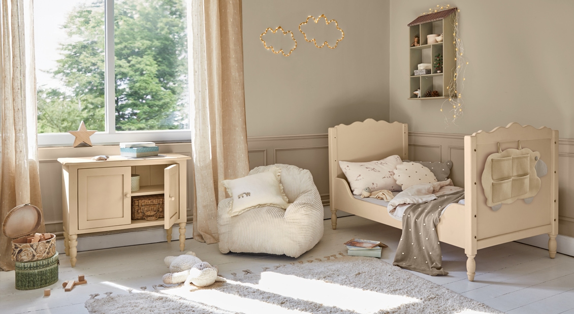 Acogedora habitación infantil con cama de madera beige, sillón suave y cómoda, decoración luminosa